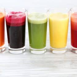 five colorful vegetables juices in glasses on table.