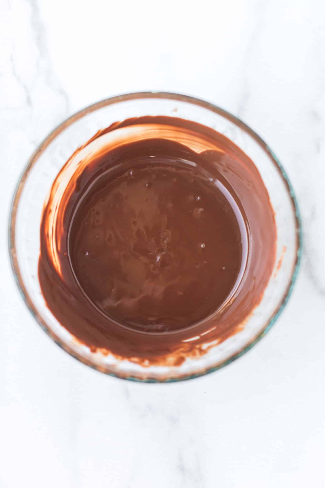 melted chocolate chips in a glass bowl ready to be poured into the heart molds.