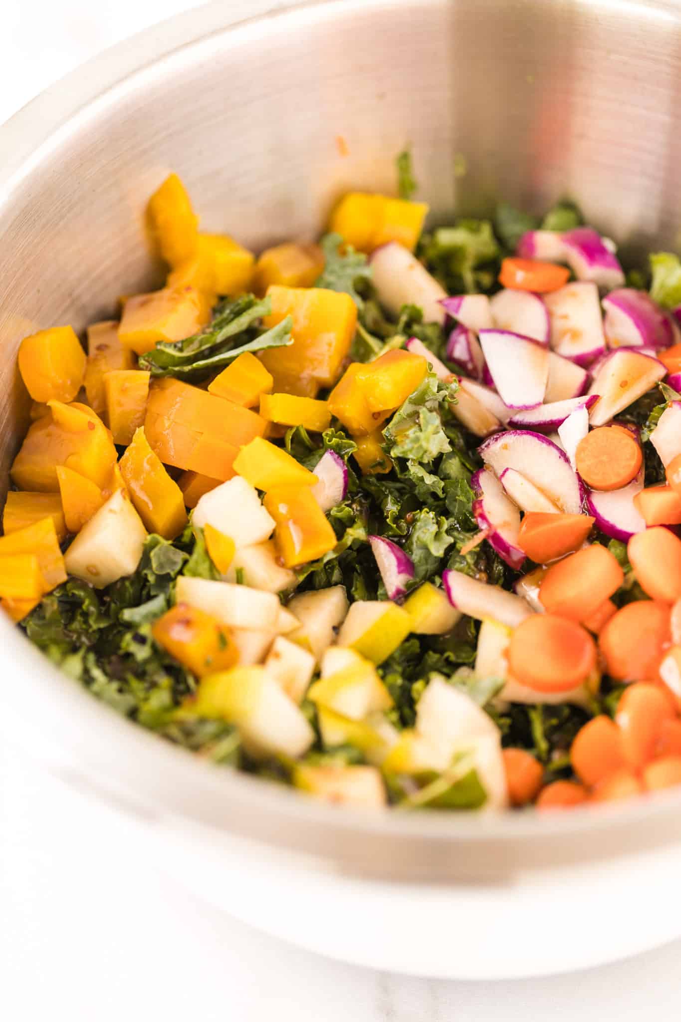 kale salad with winter vegetables tossed together in a bowl