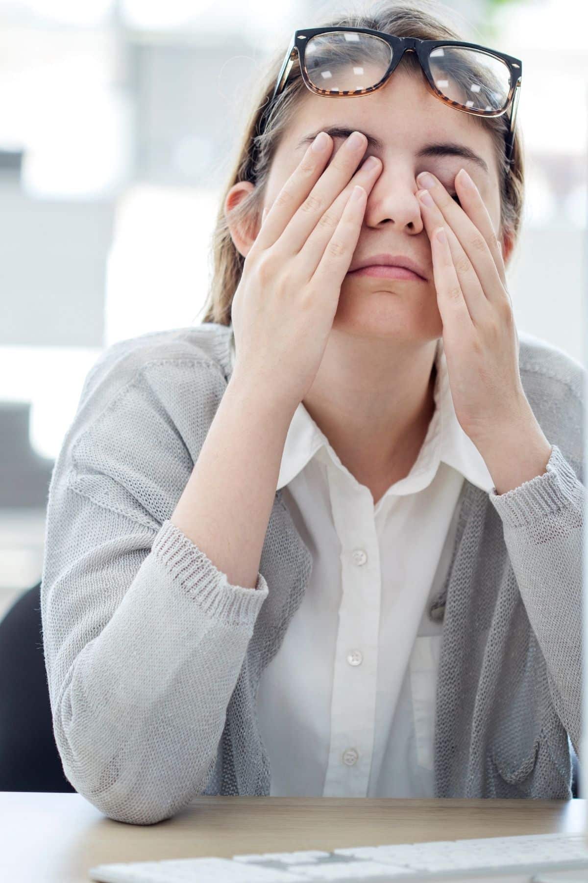 tired woman holding her hands over her eyes.