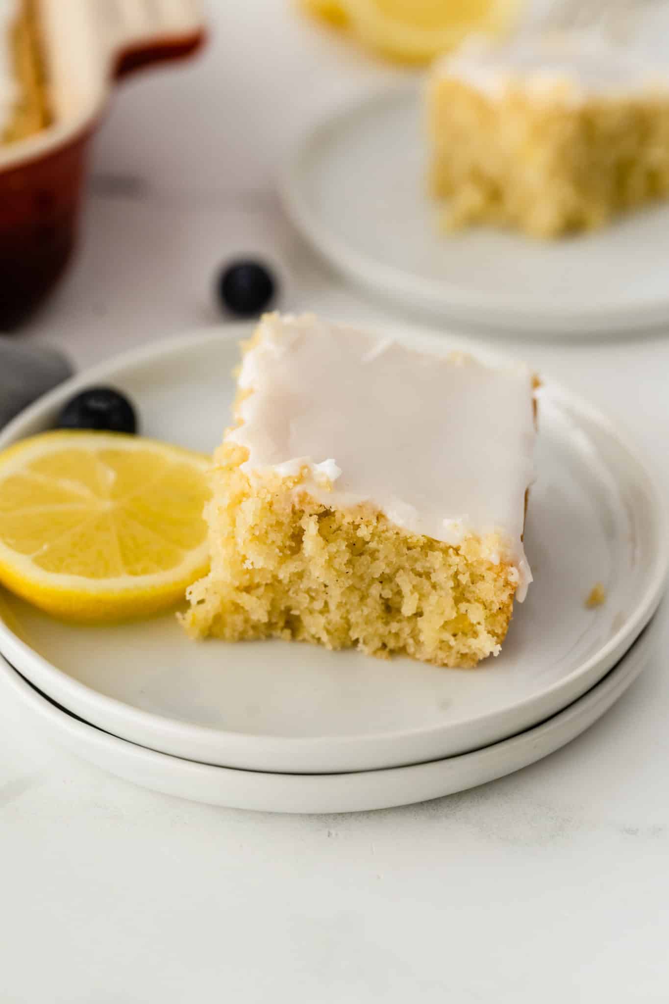 slice of gluten-free lemon cake with icing on top served with a piece of fresh lemon.