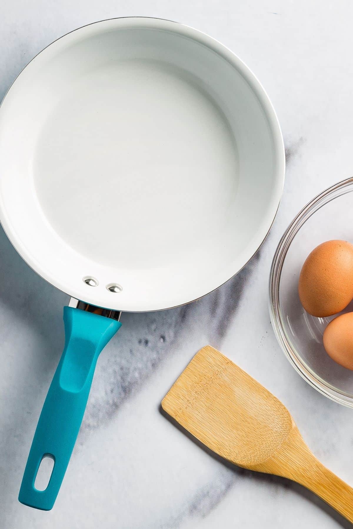 ceramic skillet on a countertop with eggs ready to be cooked.