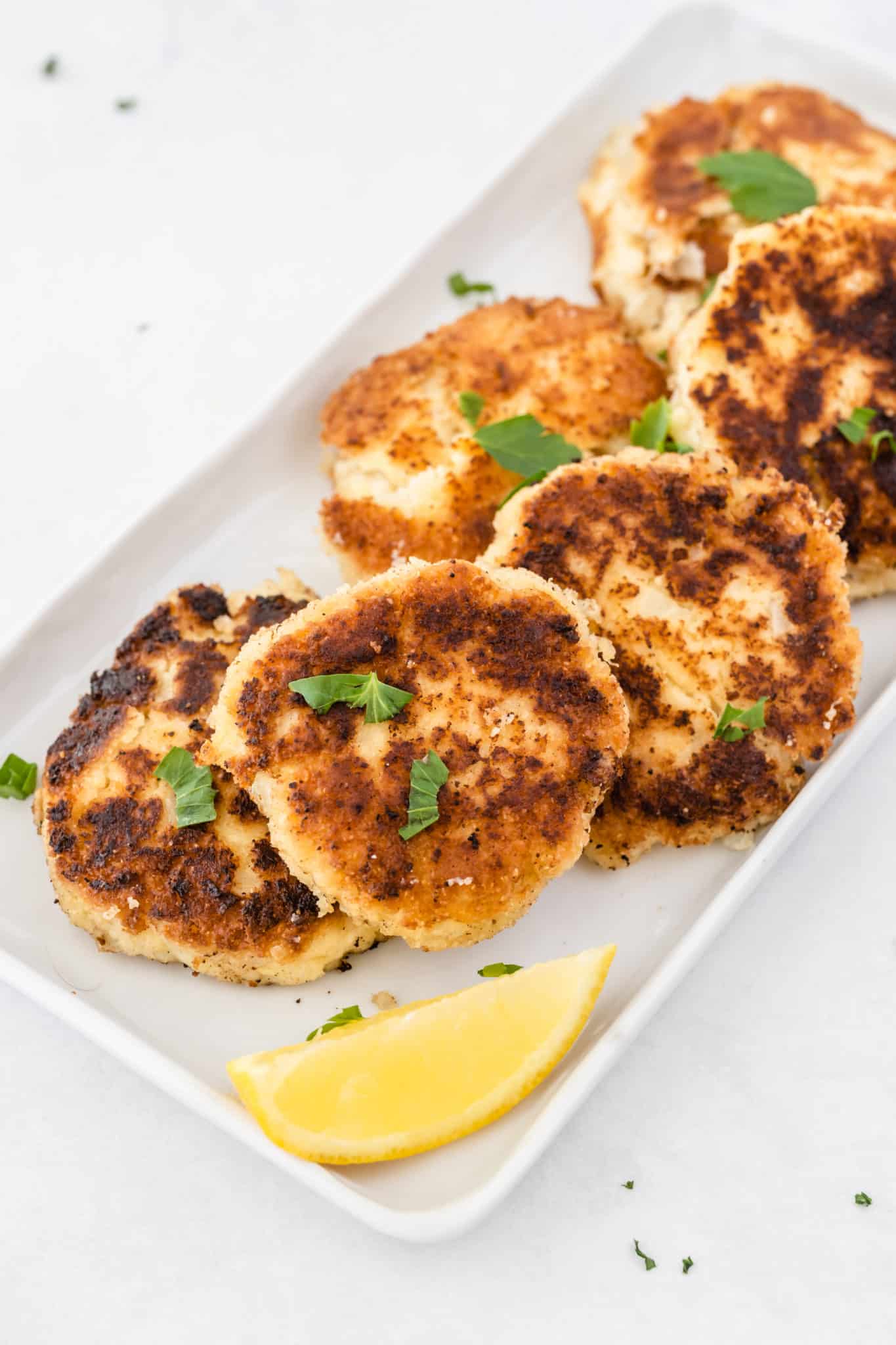 homemade gluten-free crab cakes cooked and served on a white platter.