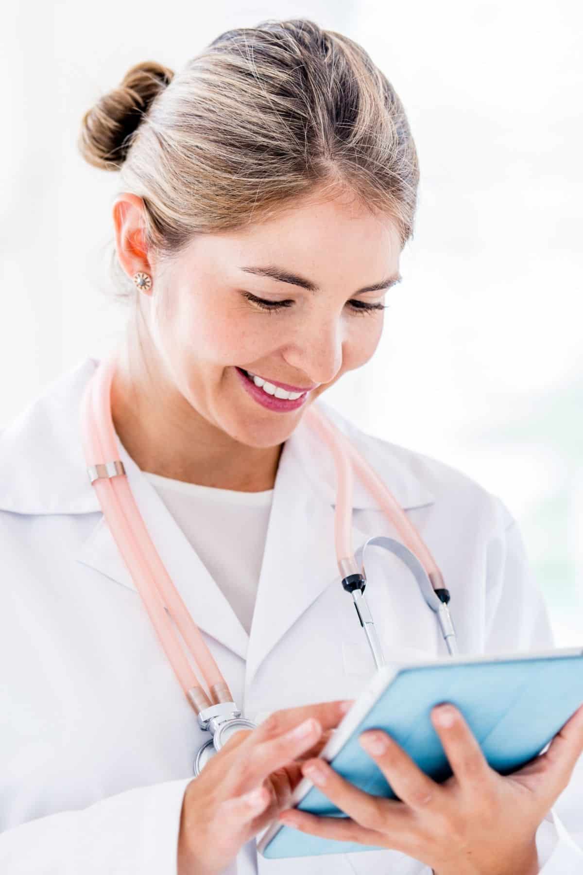 female doctor in a lab coat working on an iPad.