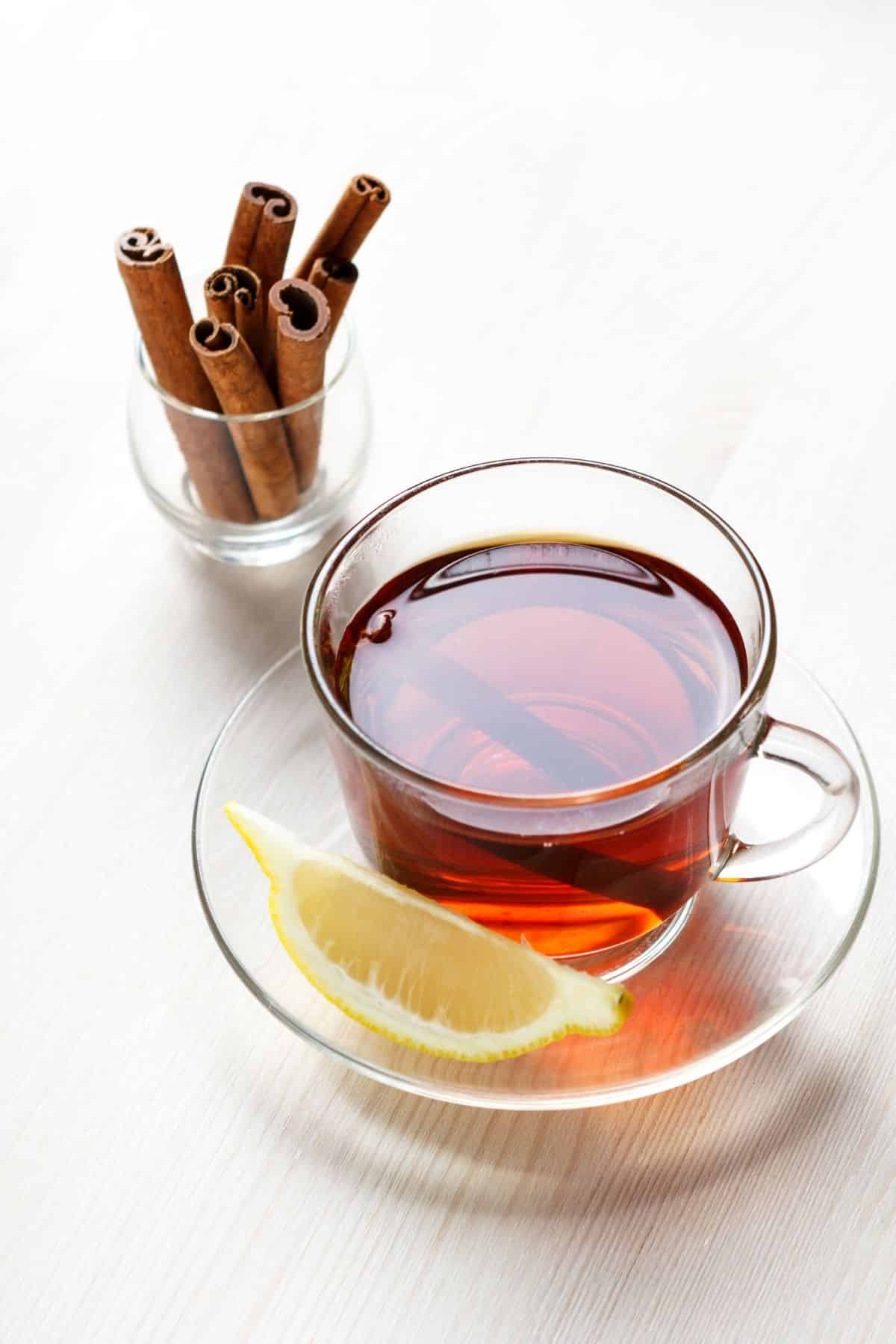 cinnamon tea served in a glass mug with a slice of fresh lemon.