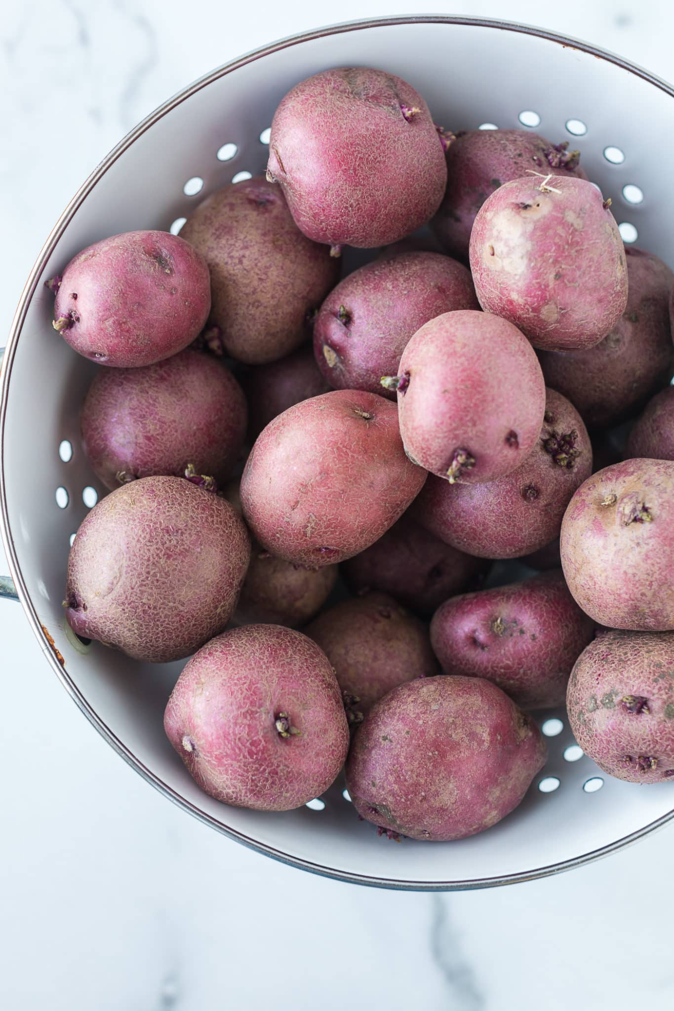 uncooked red potatoes in a colander.