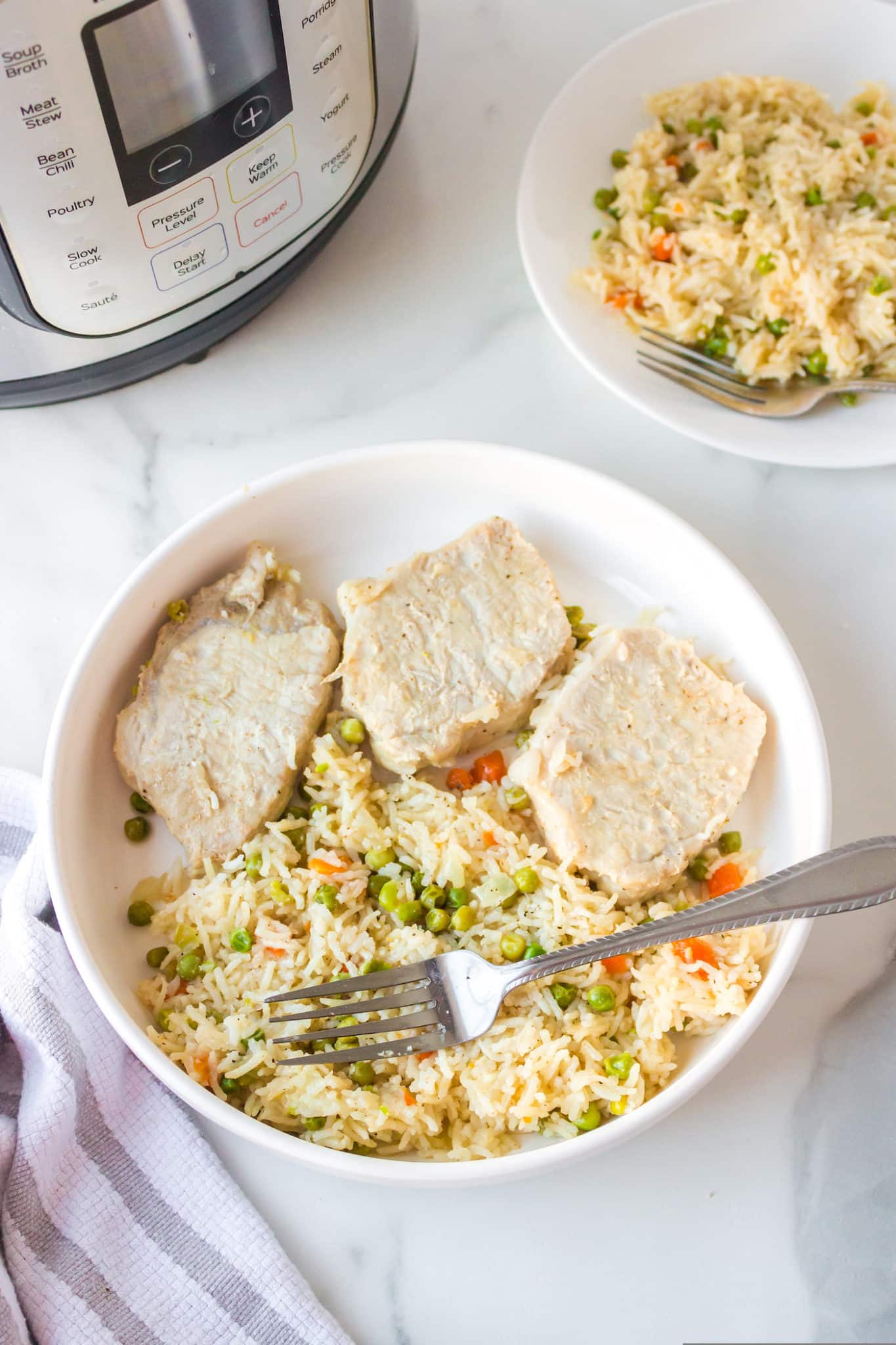 bowl with three pork chops served with rice and veggies and a fork.