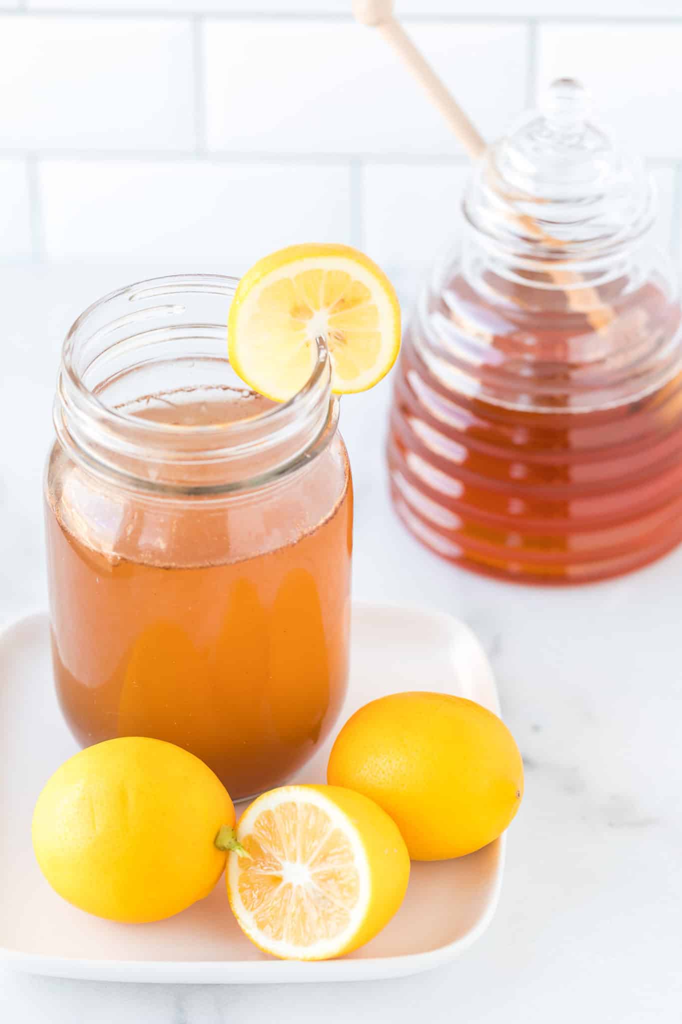 mug filed with lemon cinnamon water on a plate with fresh lemon slices.