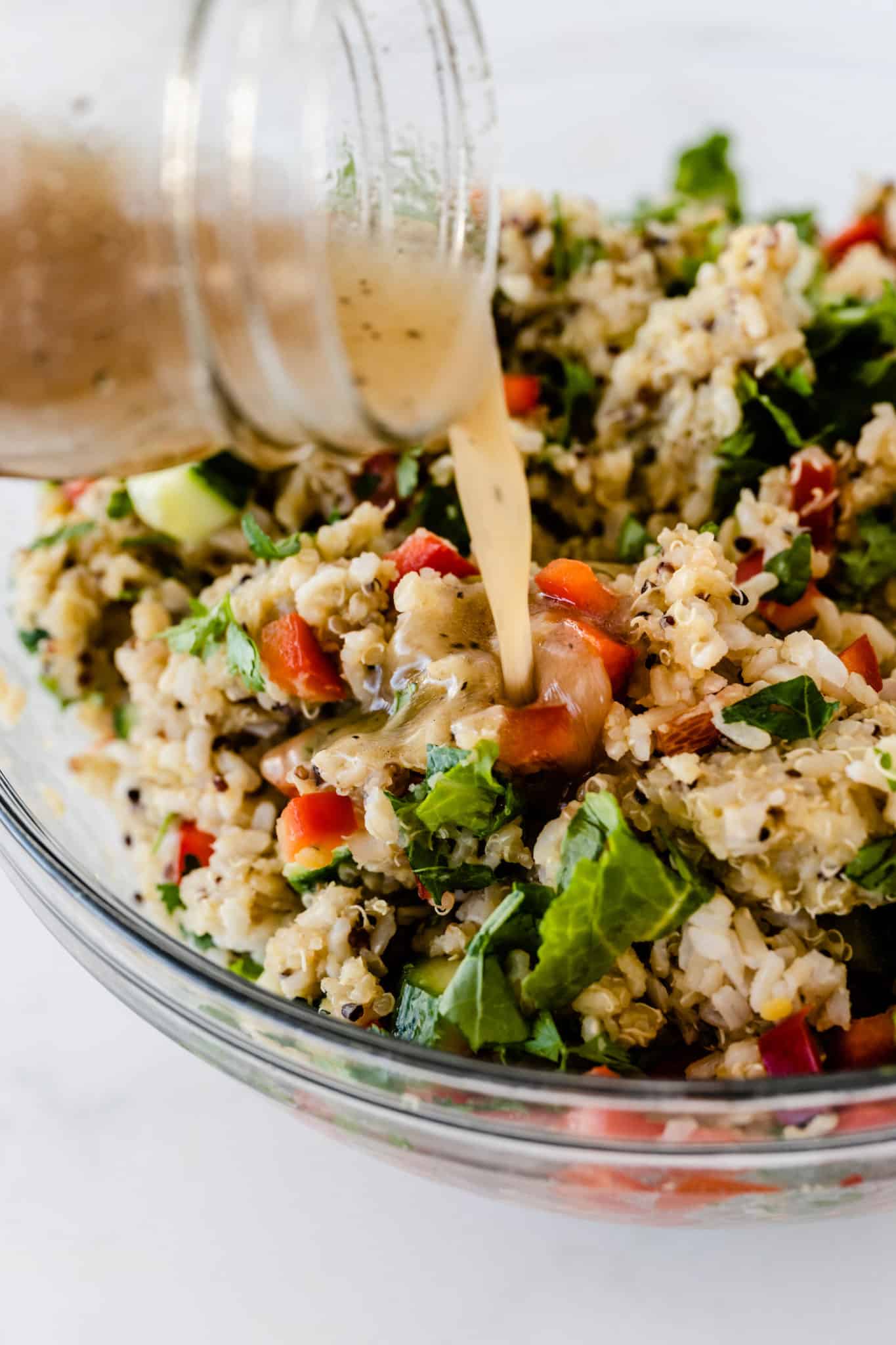 photo showing someone pouring the vinaigrette dressing onto the quinoa salad.