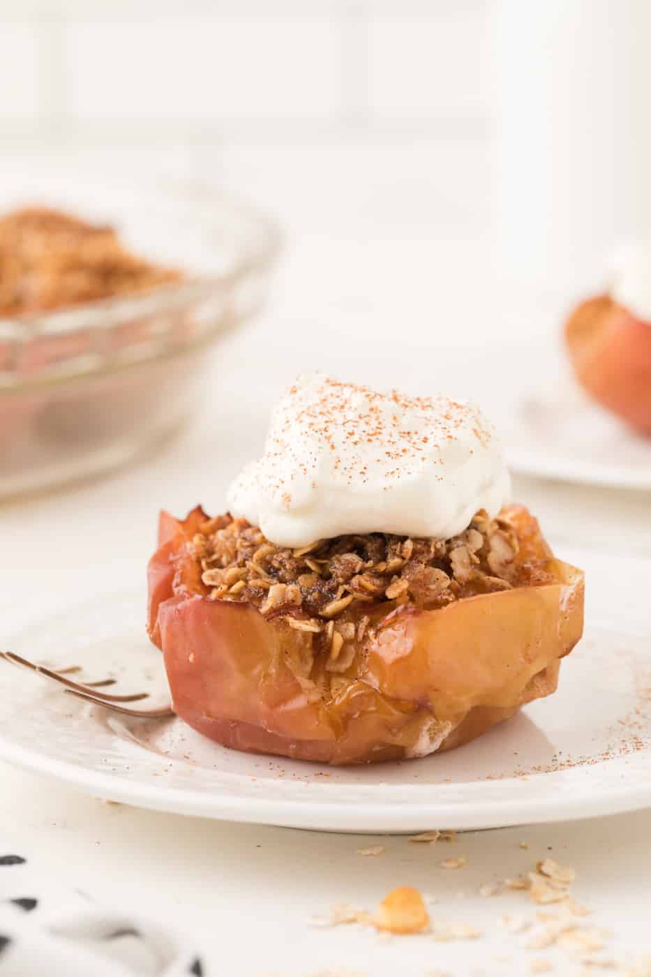 A baked apple with oat topping and whipped cream.