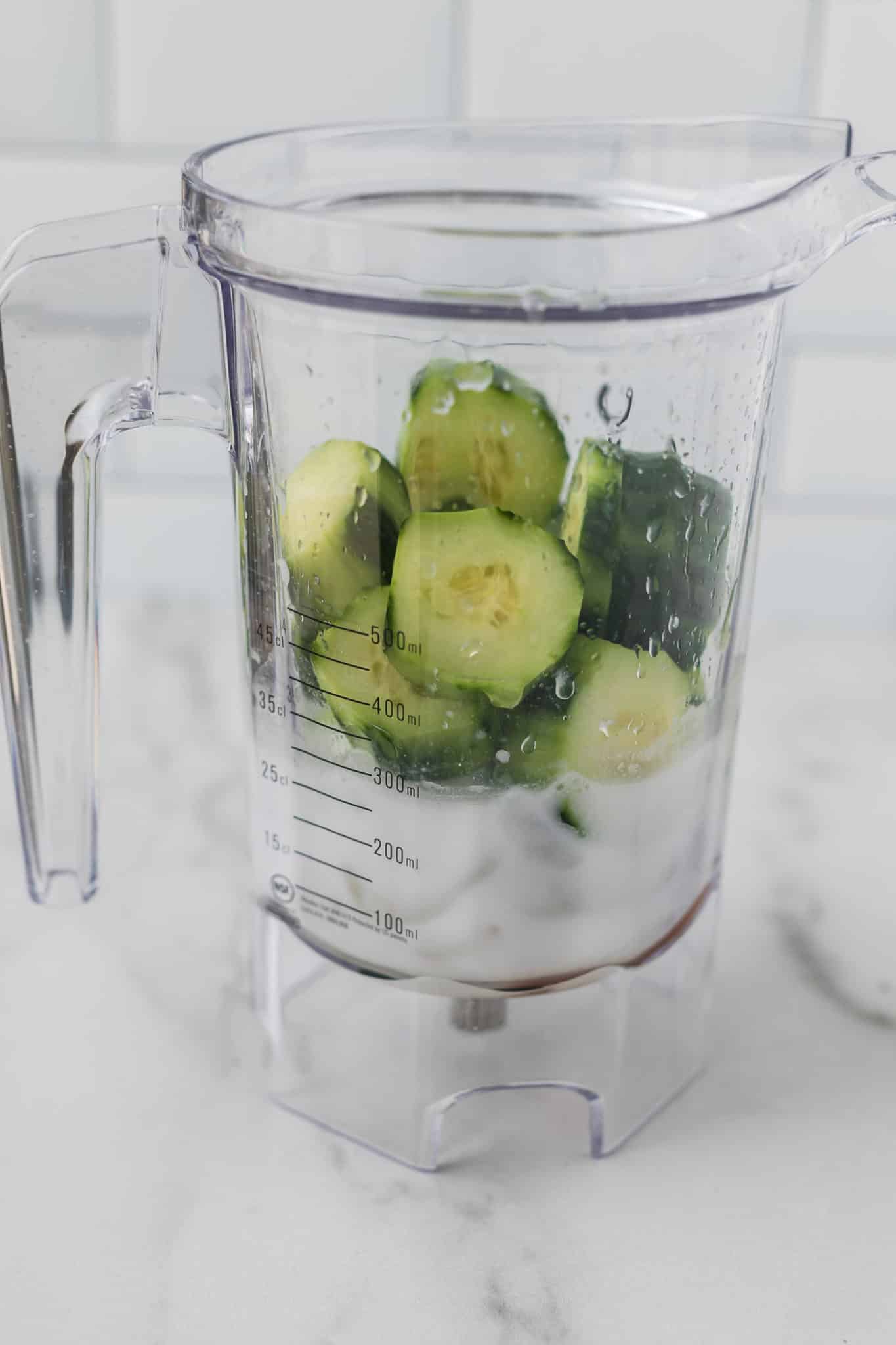 cucumber smoothie ingredients layered in a blender jar