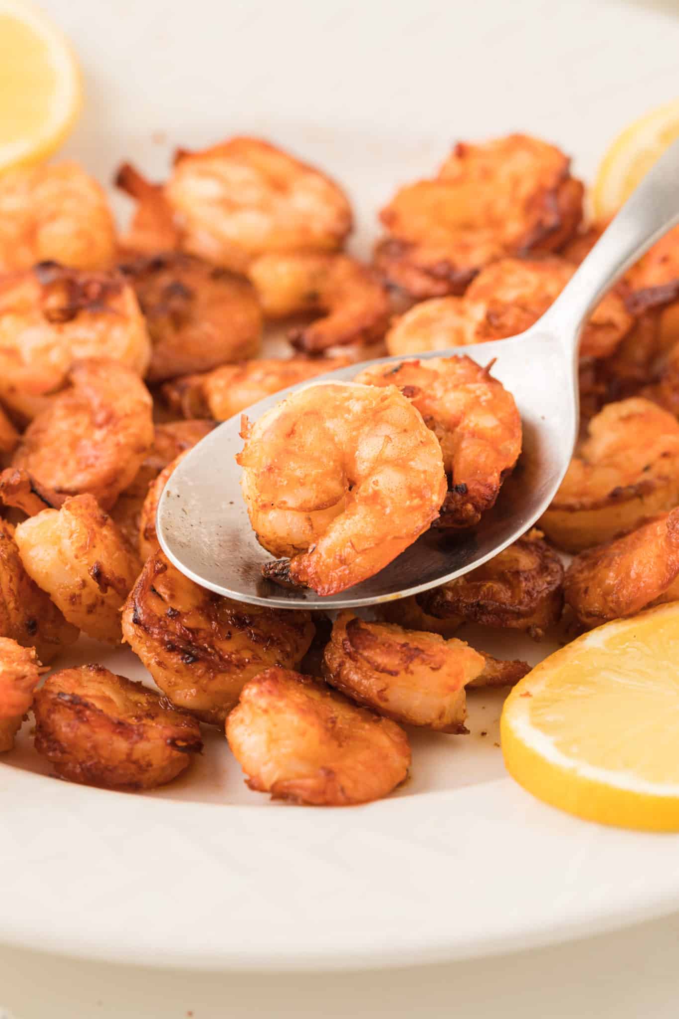 cooked air fryer shrimp on plate with lemon.