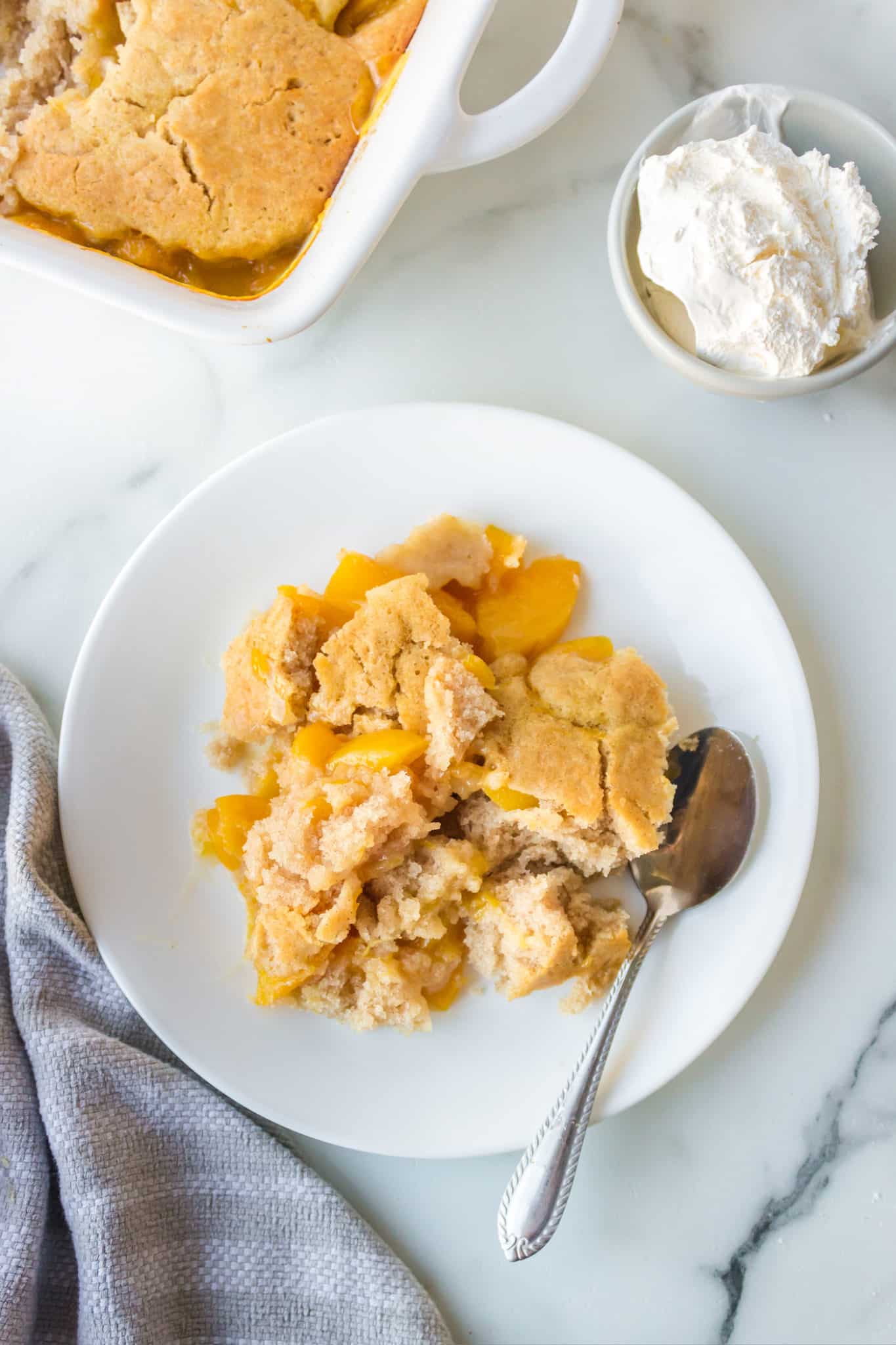 A plate of peach cobbler made with almond flour with a spoon and a napkin.