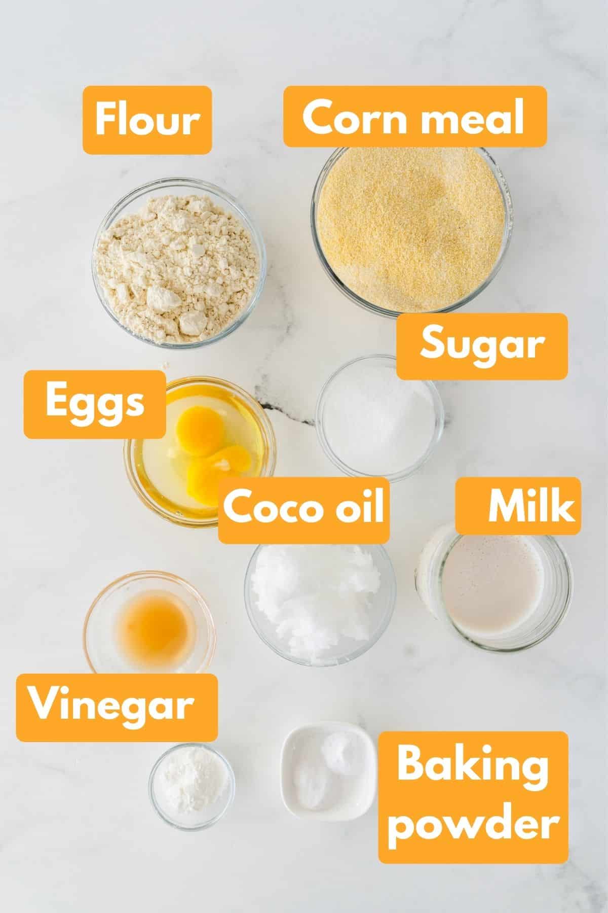 A picture of the ingredients for this recipe including flour, cornmeal, eggs, sugar, coconut oil, milk, vinegar, and baking powder. 