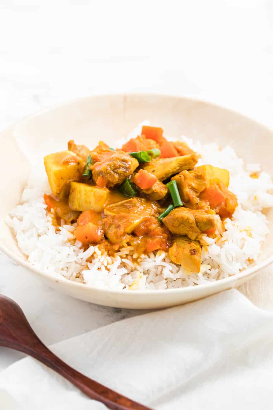 instant pot chicken curry with carrots and potatoes served in a bowl with steamed white rice.