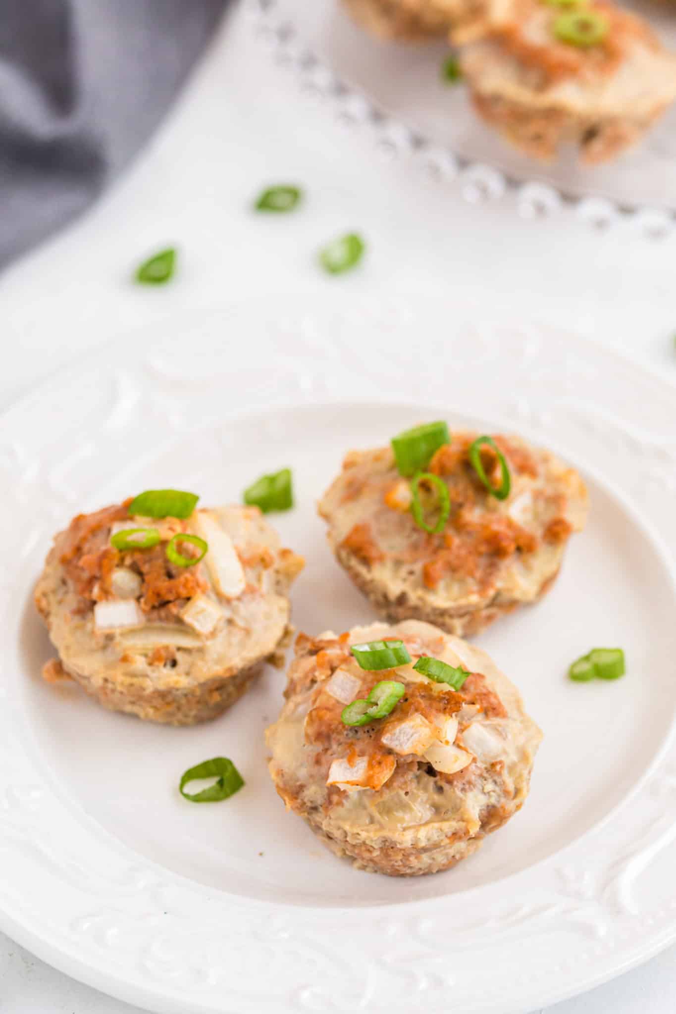 three turkey meatloaf muffins on a white plate ready to serve.