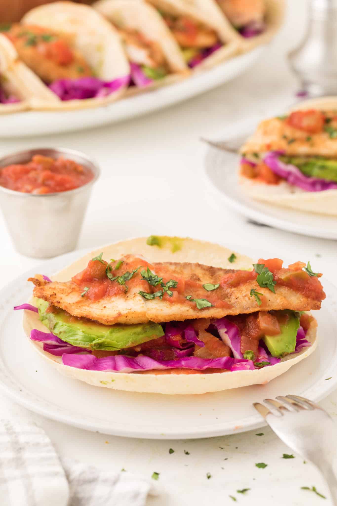 A fish taco with salsa and avocado.
