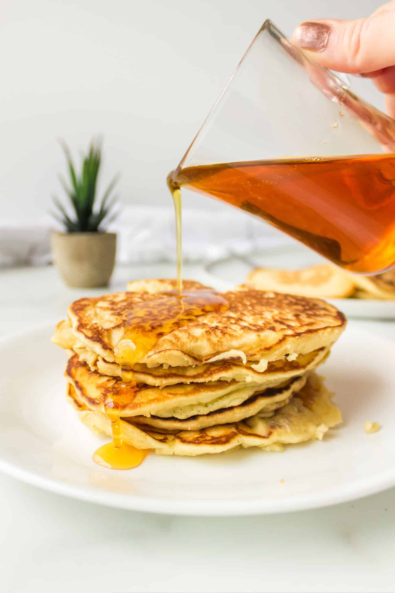 A stack of coconut milk pancakes with maple syrup.