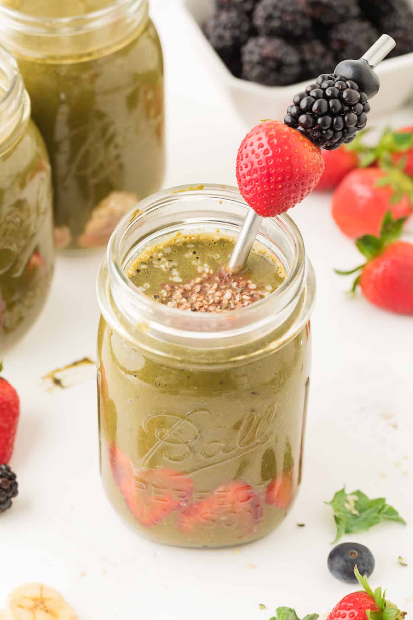 Weight loss green smoothie served in a ball jar with a berry skewer.