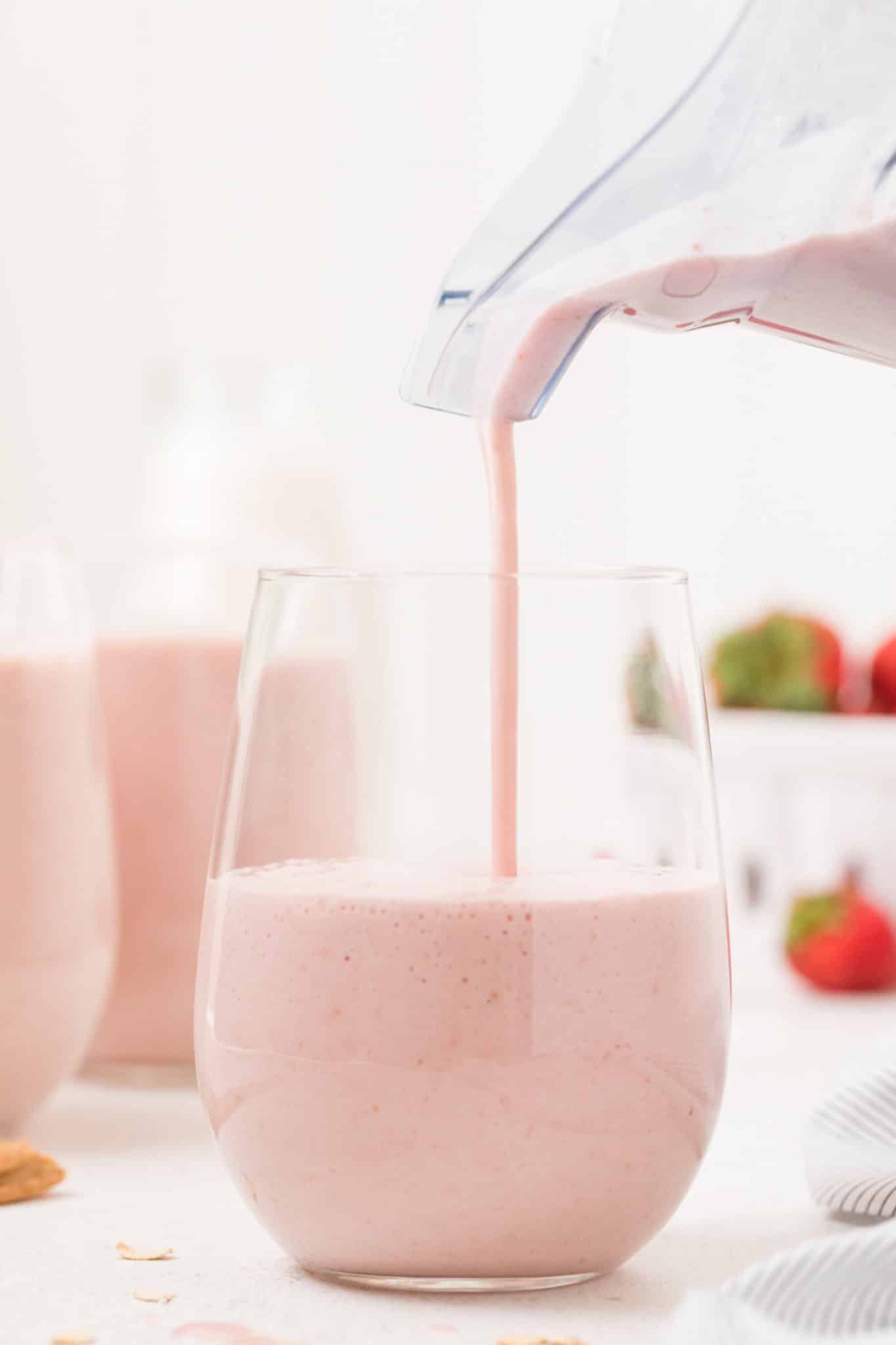 Pouring a strawberry smoothie into a glass