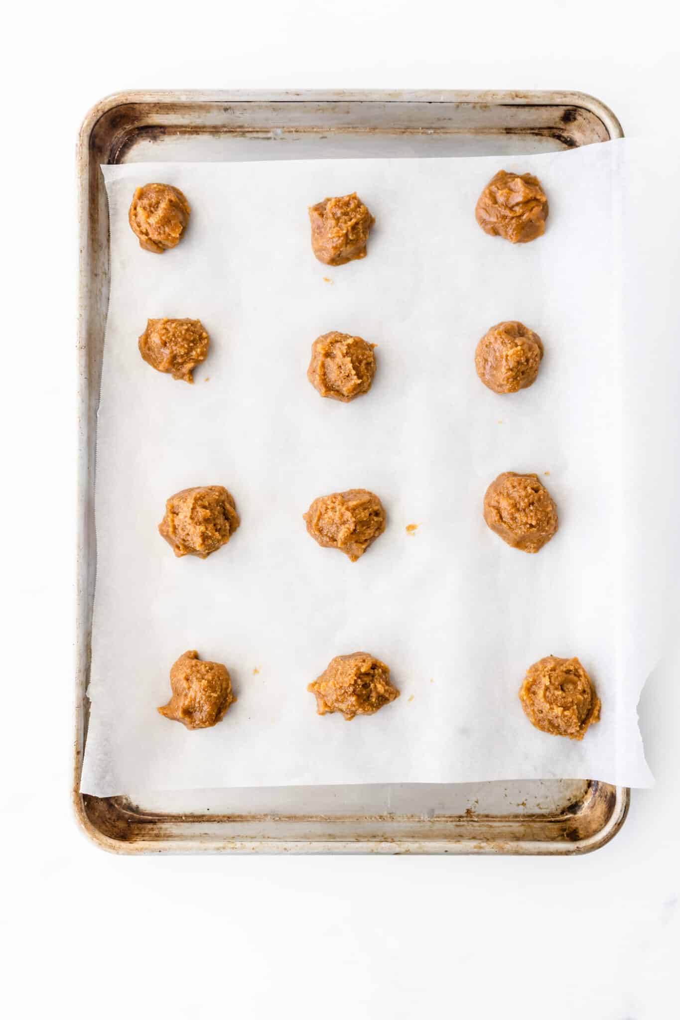 cookie dough ball on baking tray on parchment paper.