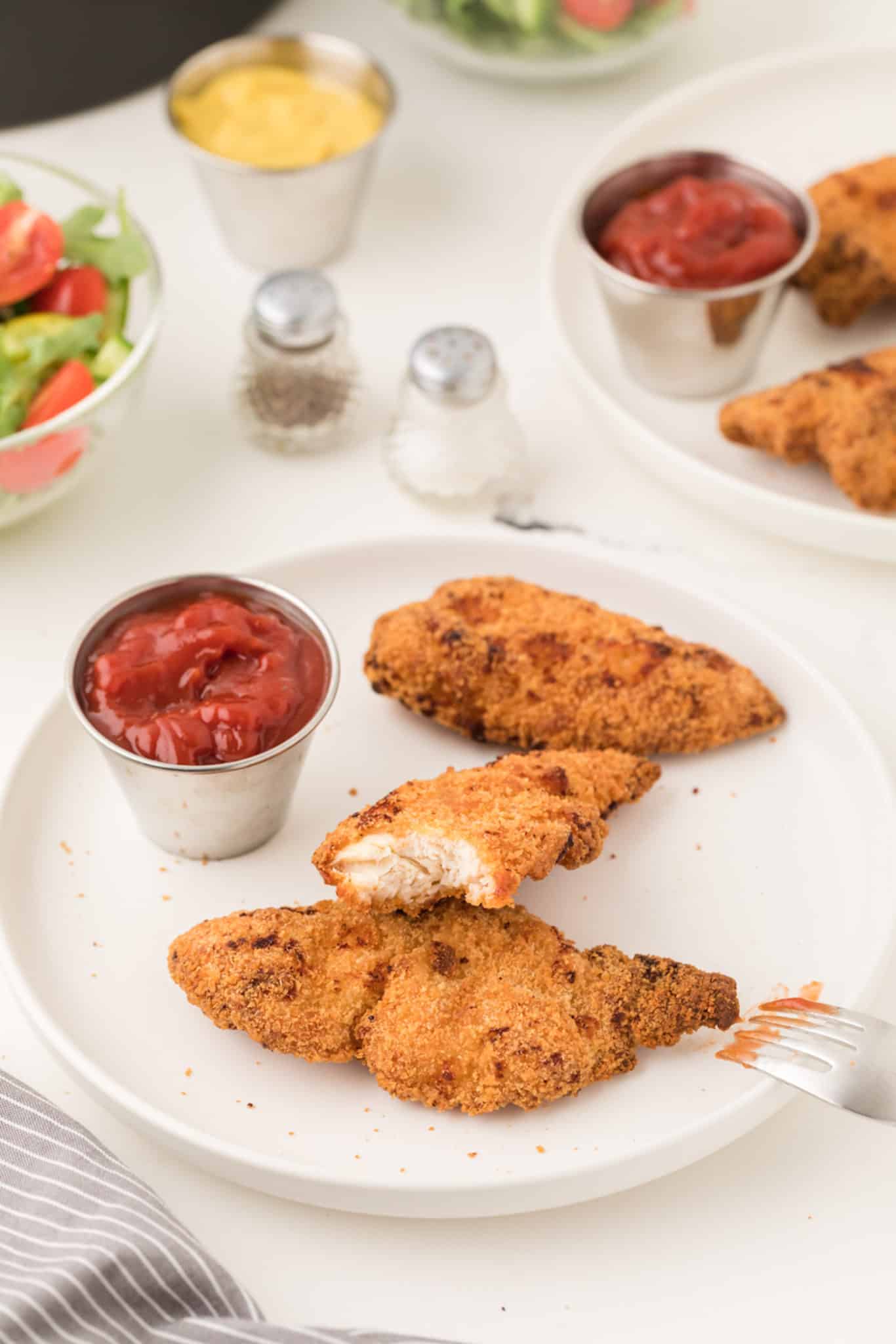air fryer chicken tenders on a plate with ketchup and a fork