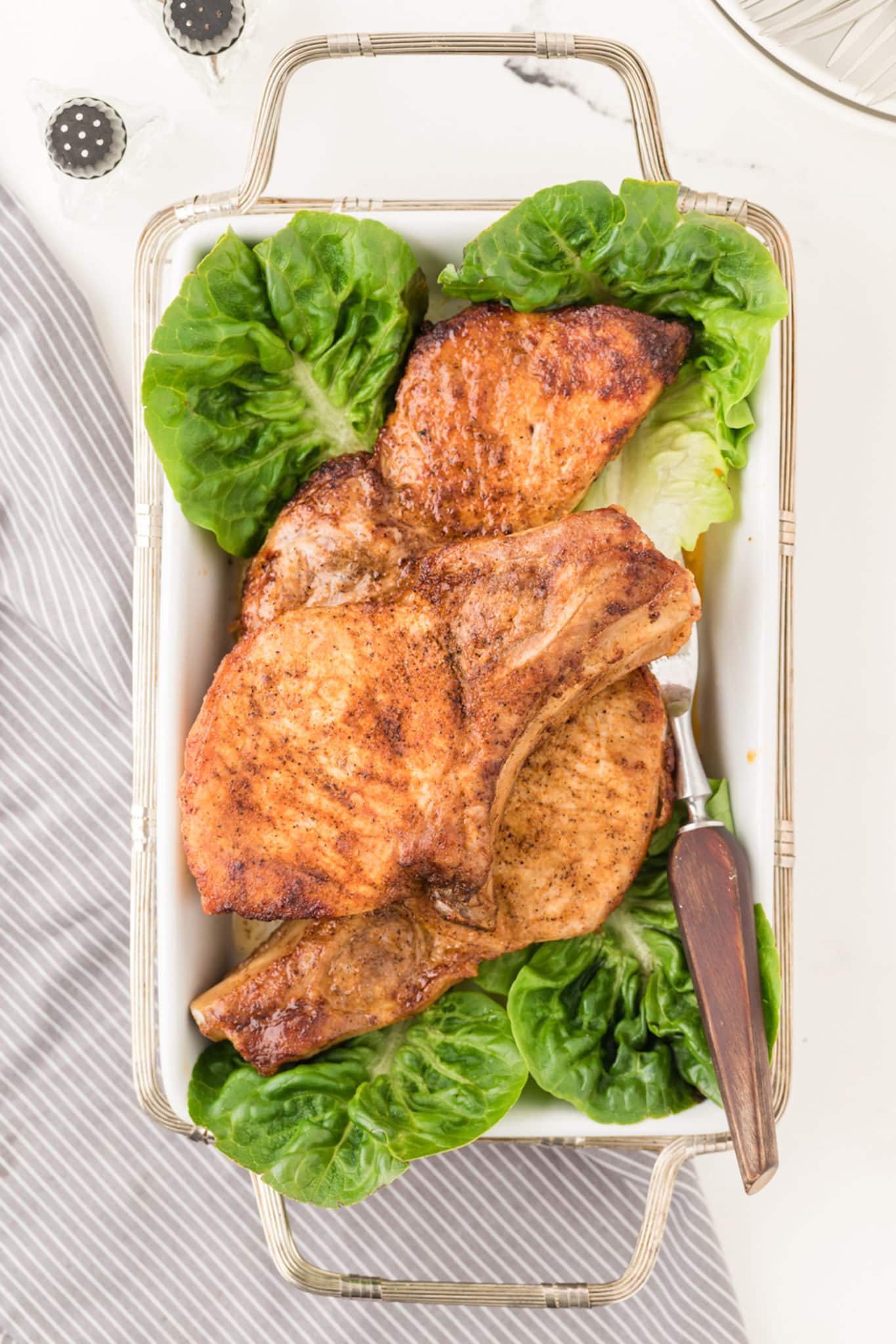 cooked pork chops on a serving dish with lettuce.
