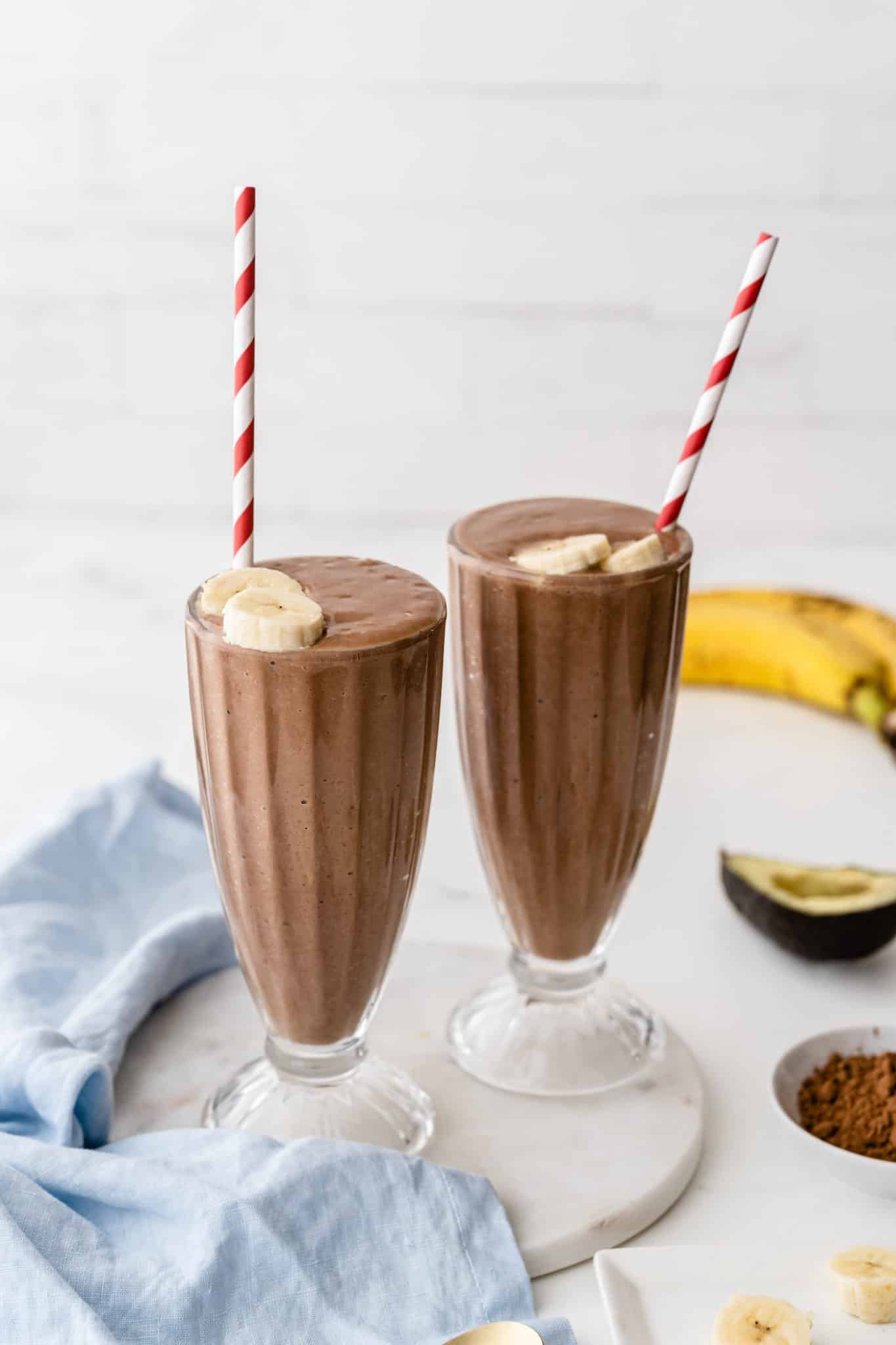 Chocolate avocado smoothies served in two milkshake glasses with straws