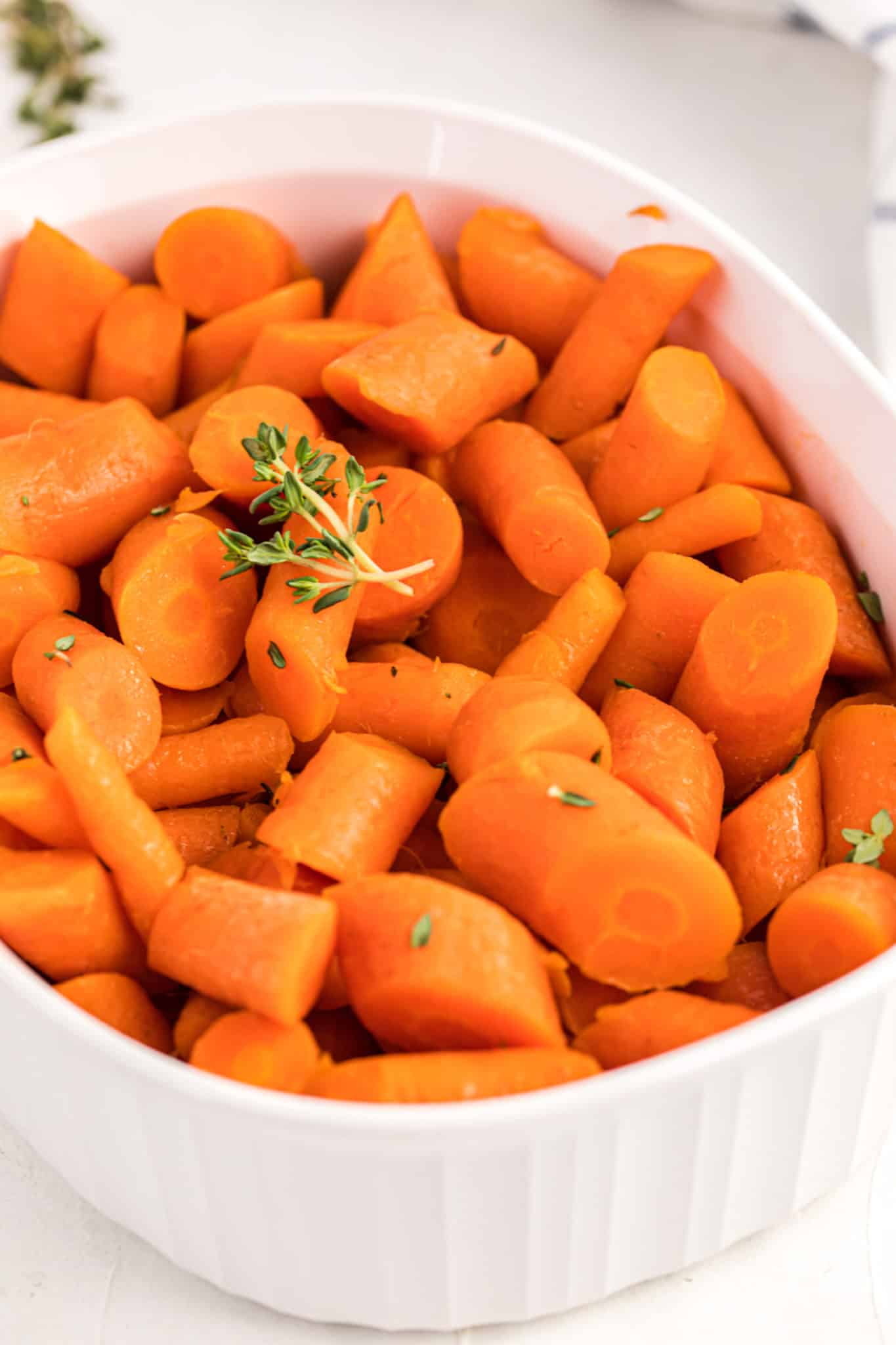 A close up of cooked carrots with fresh thyme on top.