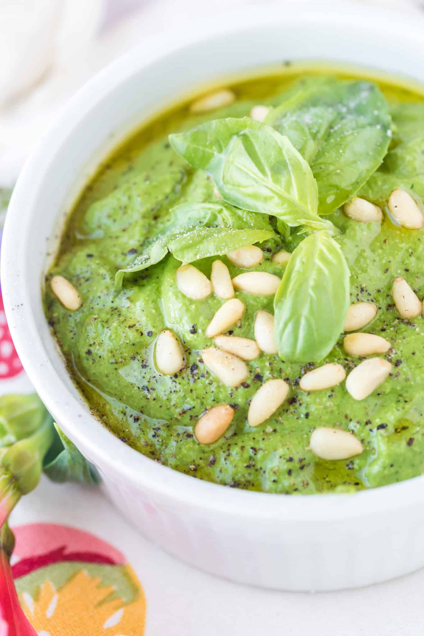 pesto served in a bowl topped with pine nuts and basil leaves