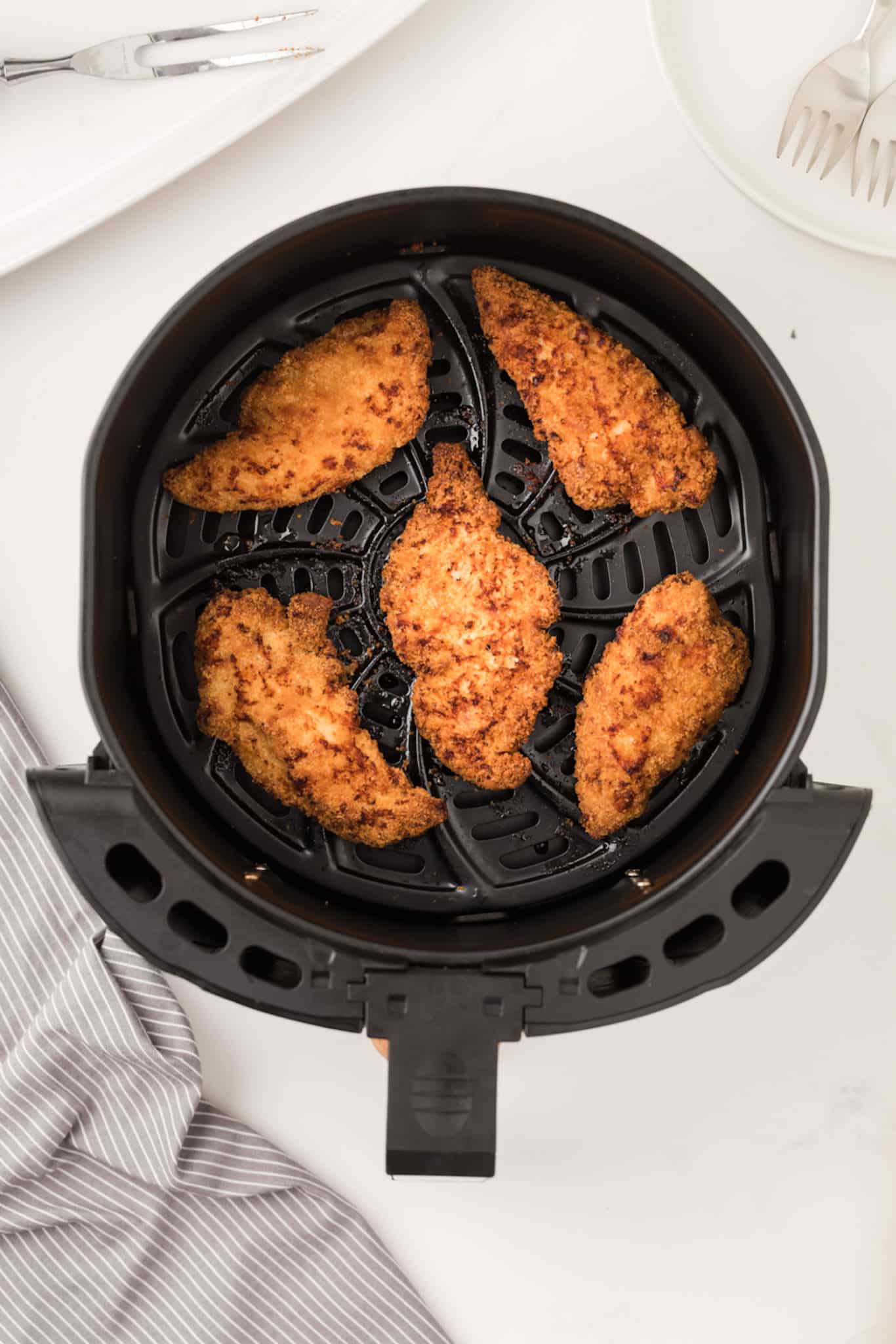 cooked breaded chicken tenders inside air fryer basket