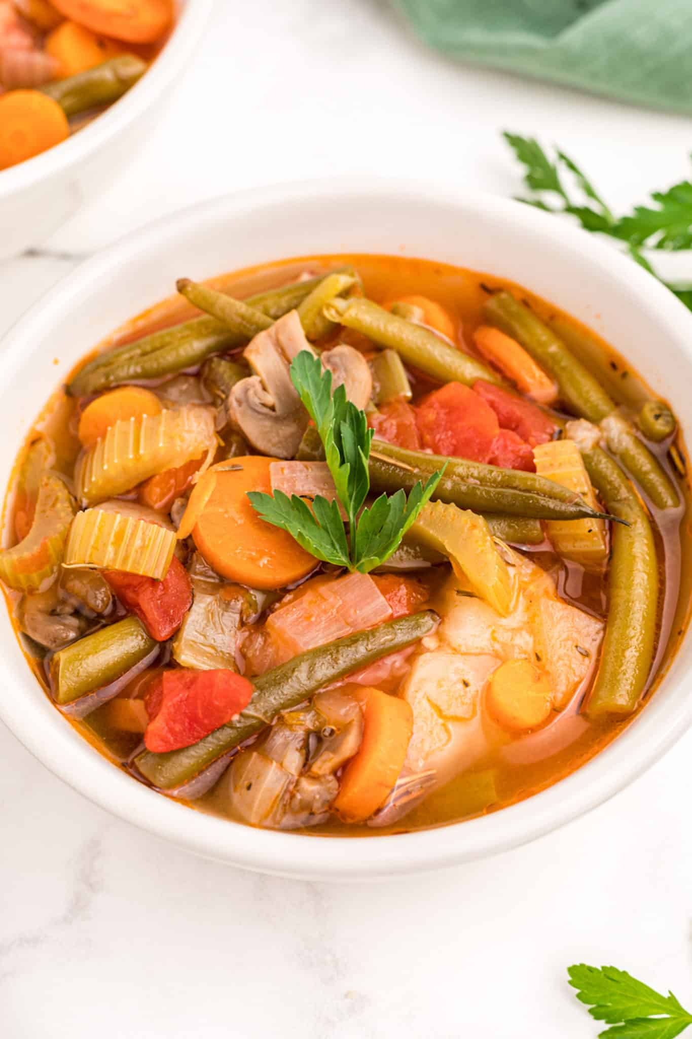 a bowl of vegetable stew with potatoes topped with parsley garnish.