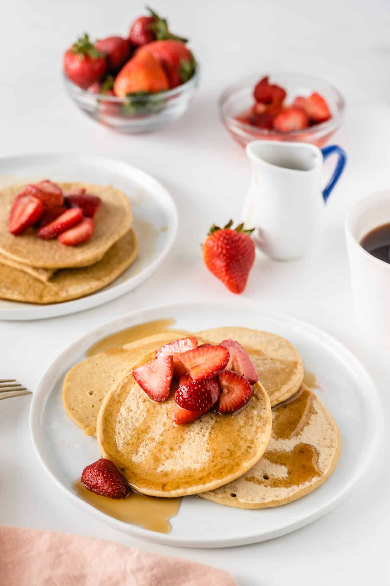 oat milk pancakes served on white plates with strawberries and coffee