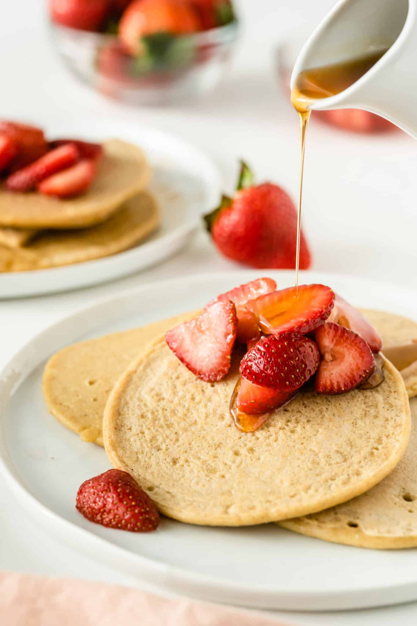 Oat milk pancakes with syrup and strawberries.