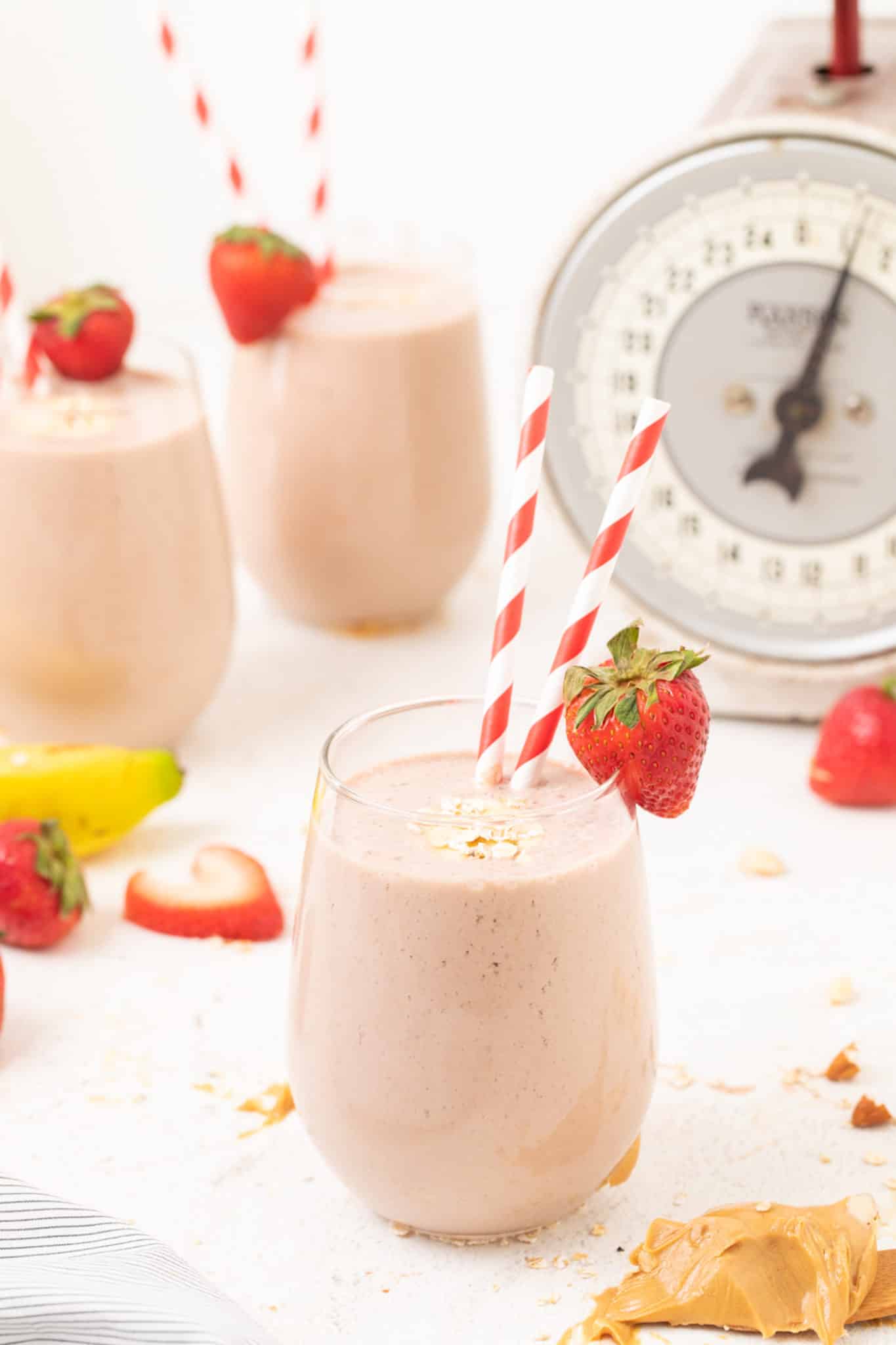 three glasses of strawberry smoothie served with straws