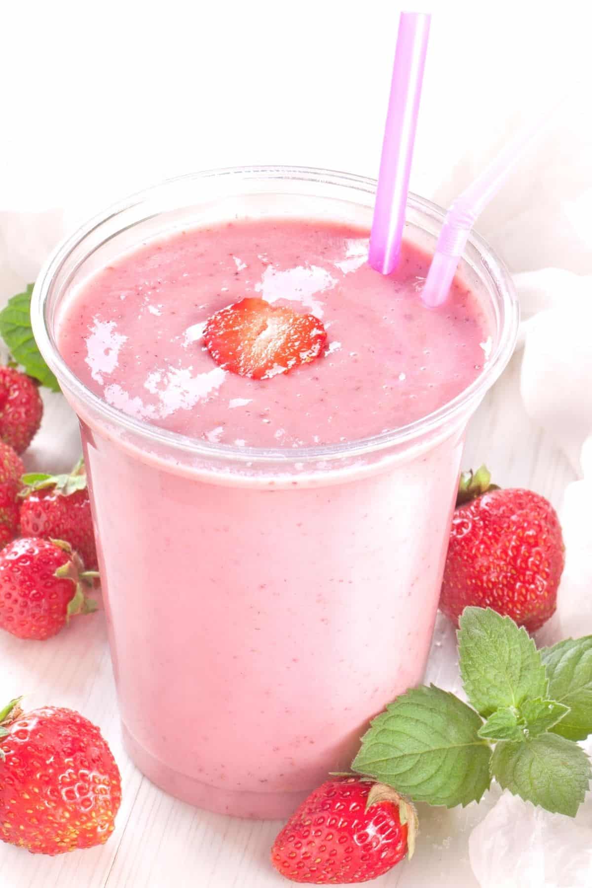 vegan strawberry milkshake served in glass with pink straws