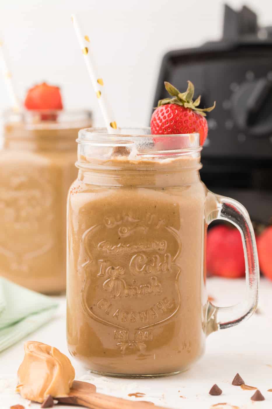 Creamy chocolate smoothie served in glass with straw.