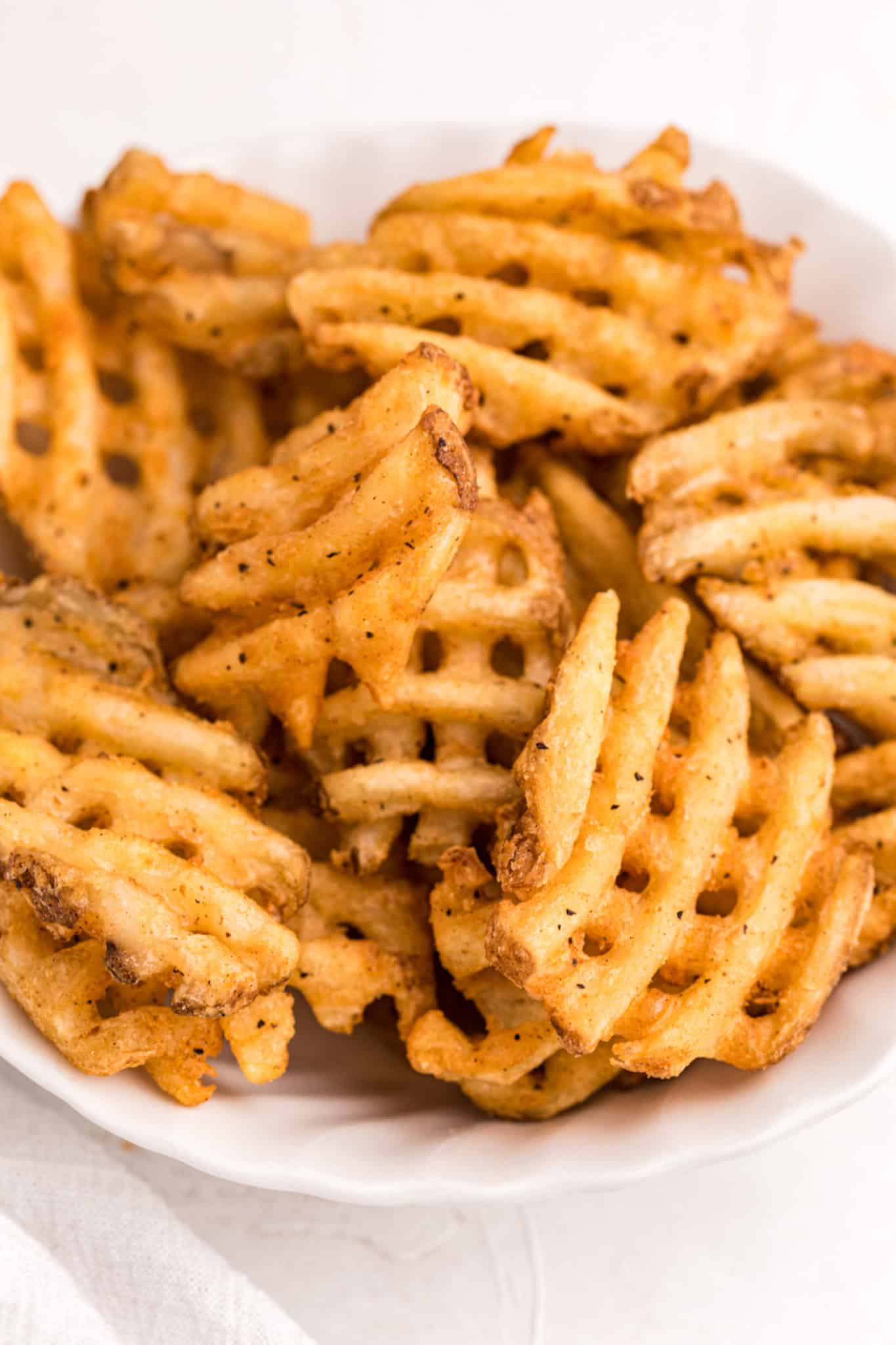 crispy waffle fries served in a white bowl.