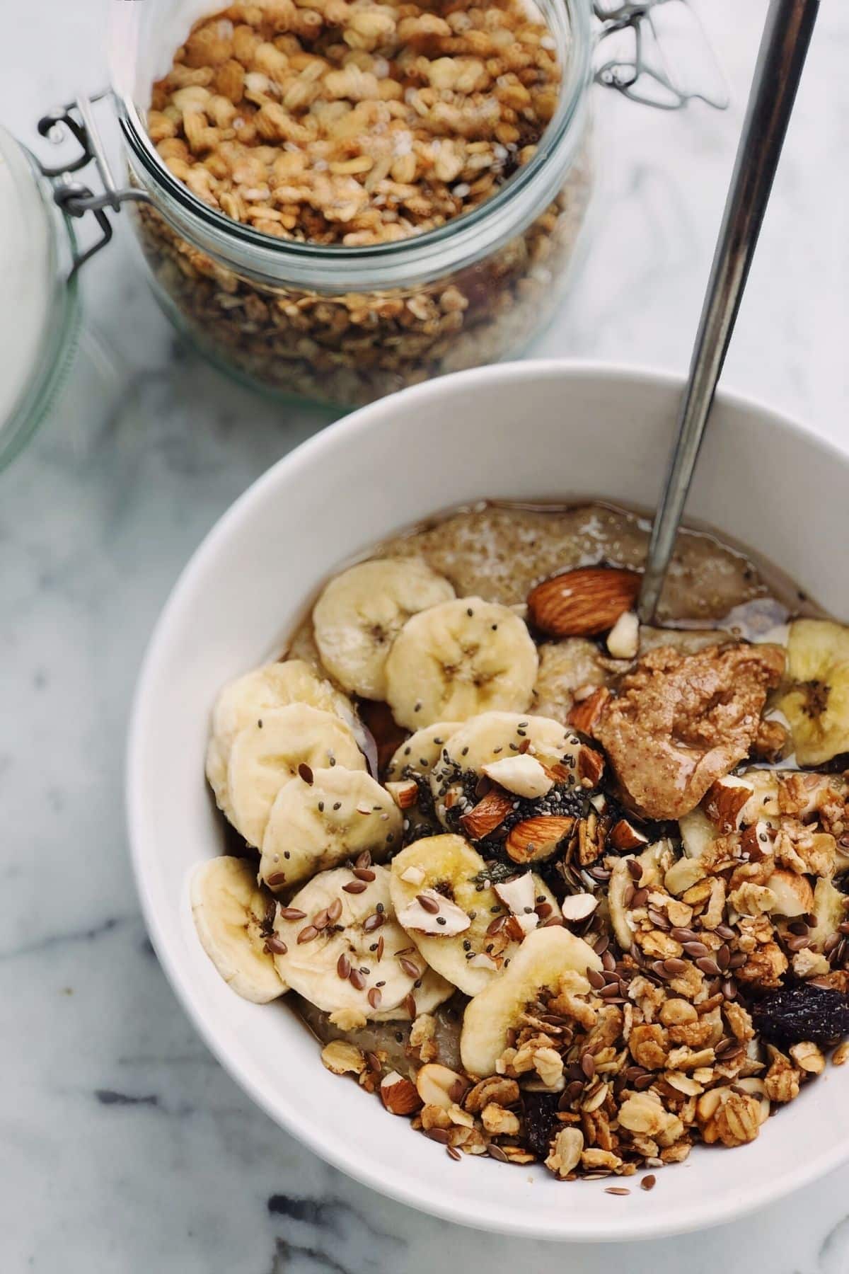 bowl of granola served with a sliced banana and nut butter.