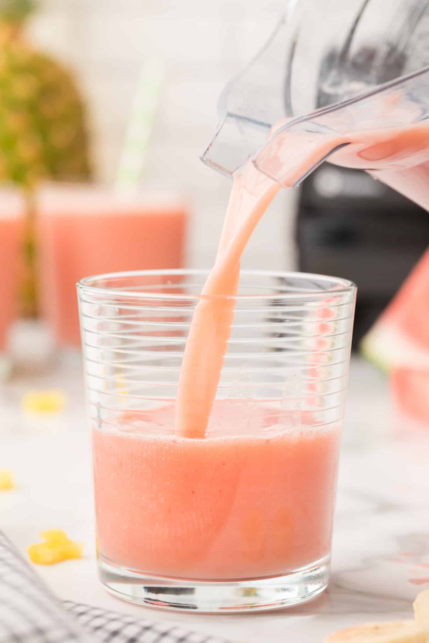 picture pouring pink watermelon banana smoothie into glass.