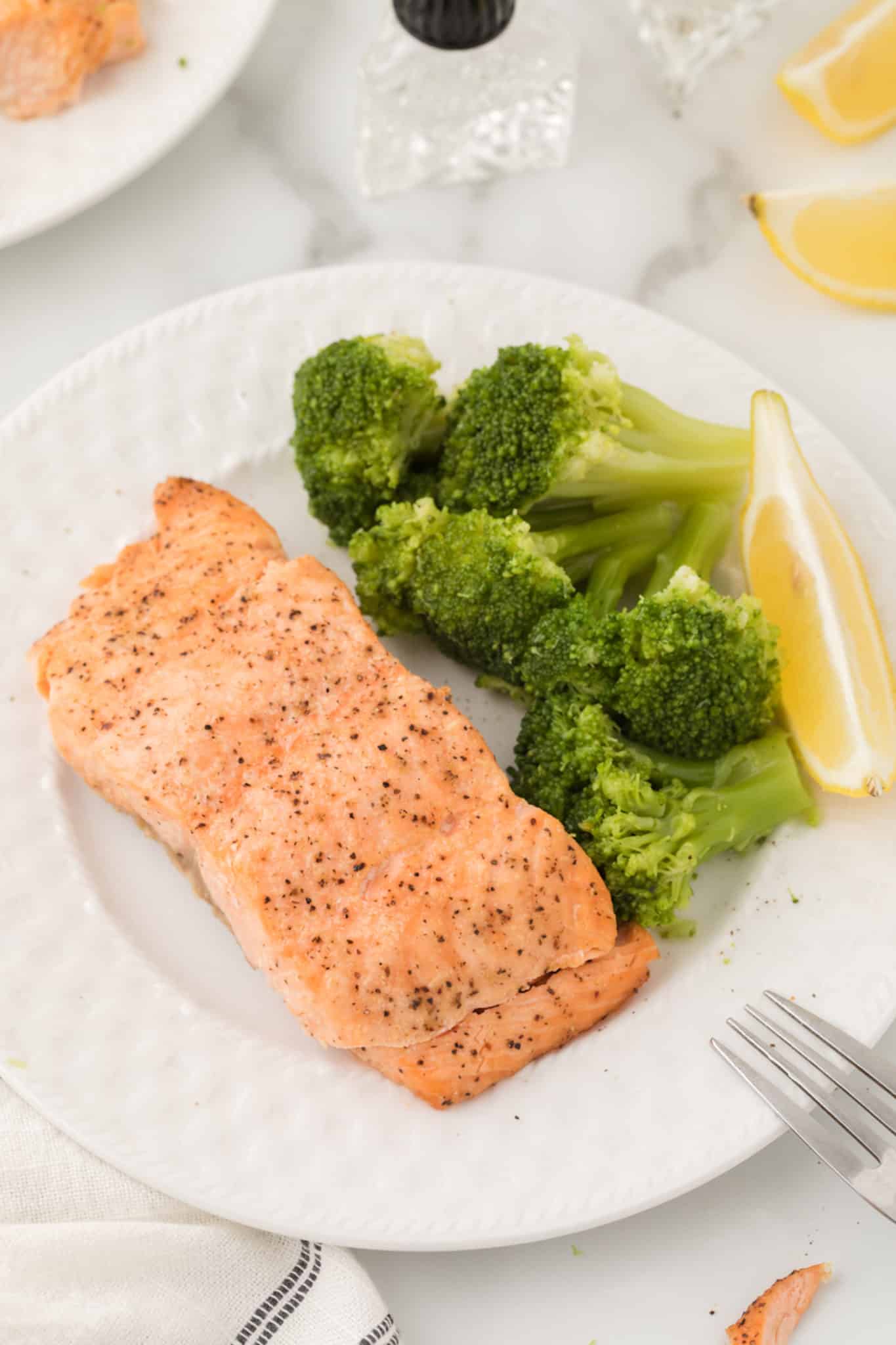 air fried salmon on plate with broccoli and lemon.