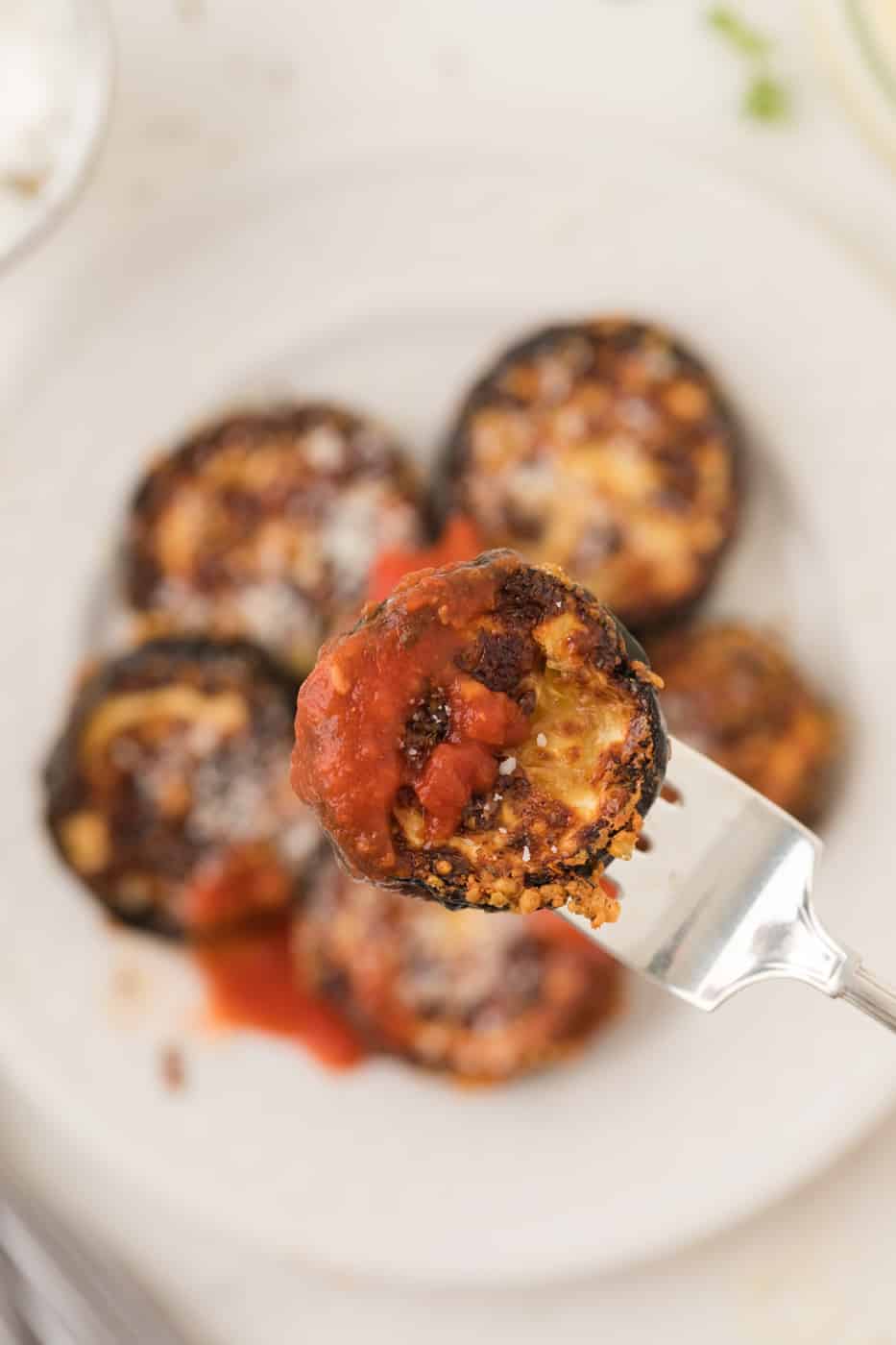 cooked zucchini chip on a fork with marinara