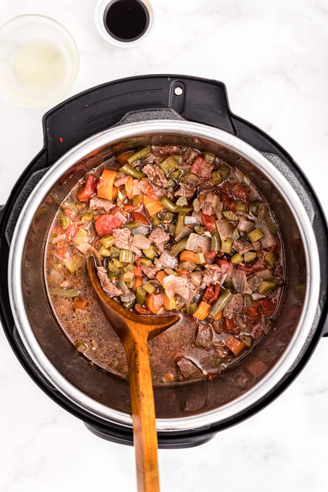 cooked vegetable beef soup with serving spoon in instant pot.
