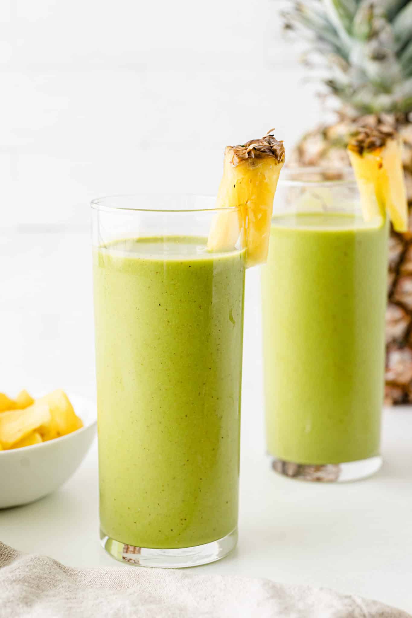 mango pineapple spinach smoothie served in two glasses