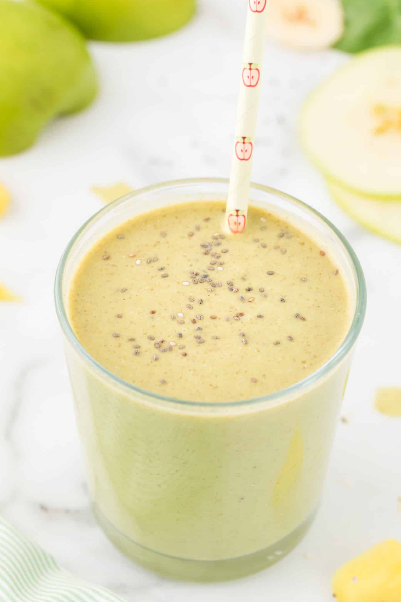 green spinach apple banana smoothie served in glass and topped with chia seeds.