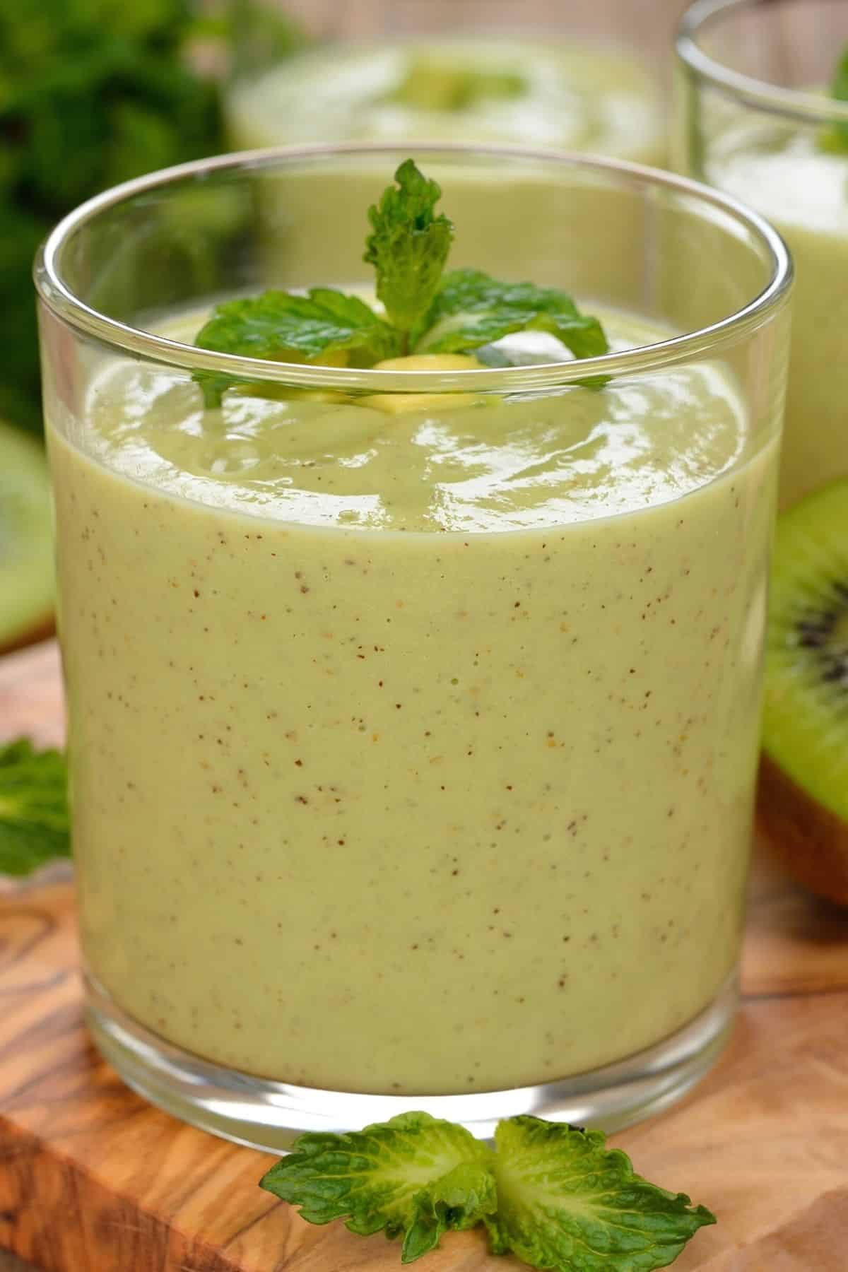 glass of green kiwi smoothie with fresh mint on top.