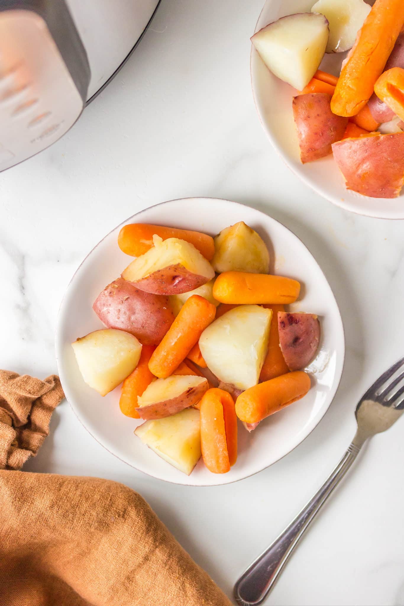 cooked instant pot potatoes and carrots served on a white plate.