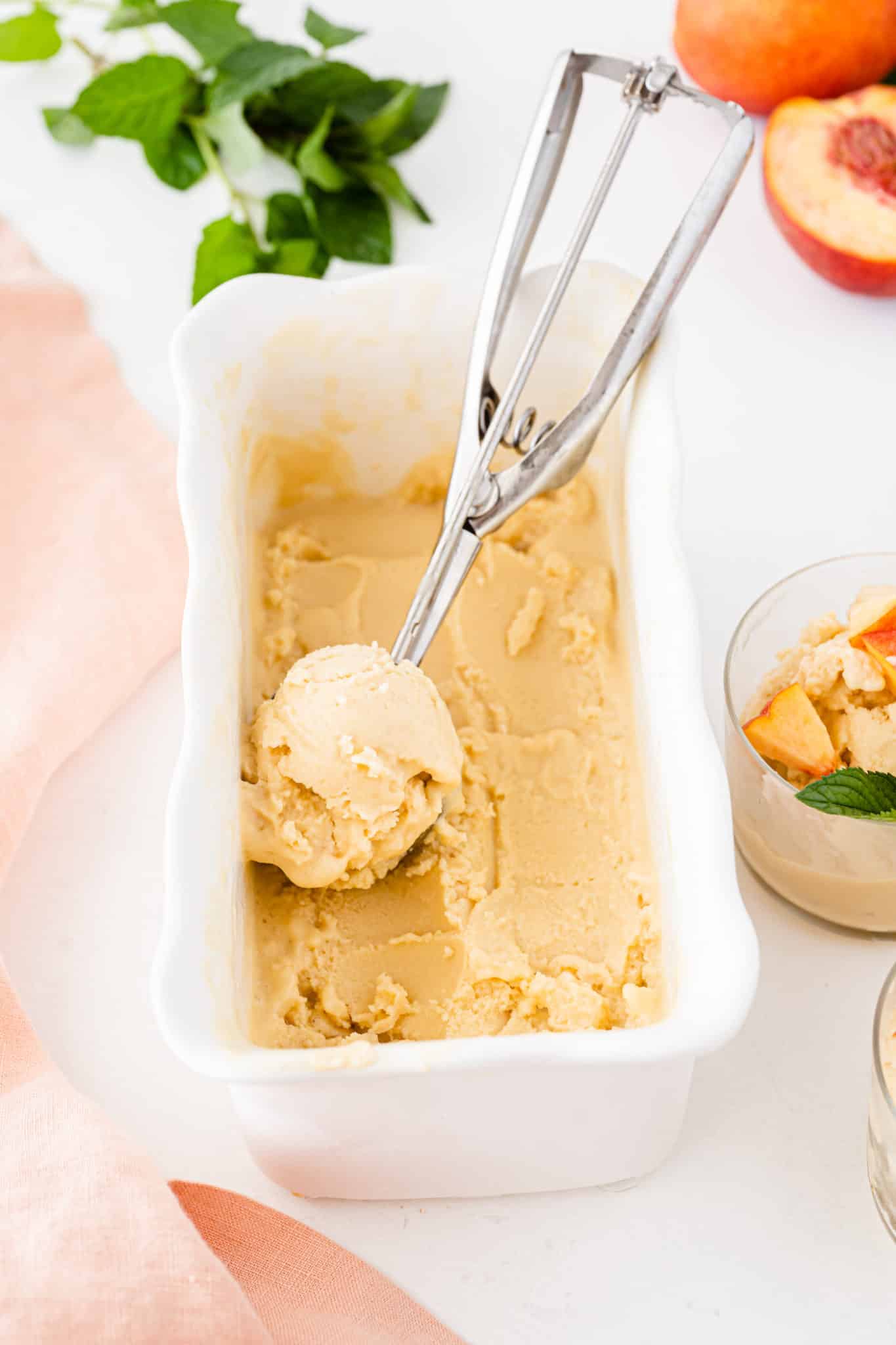 peach ice cream in container with scooper.