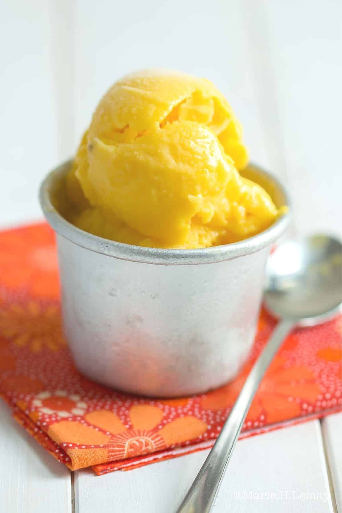 mango sorbet in a cup with spoon.