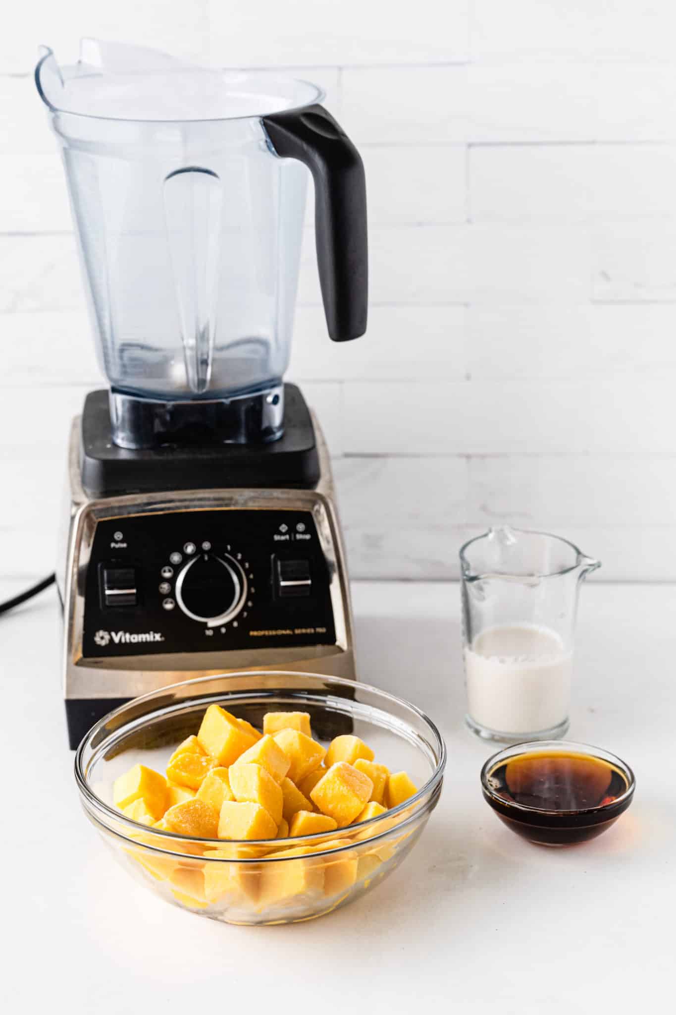 a Vitamix blender, frozen mango, and dairy-free milk.